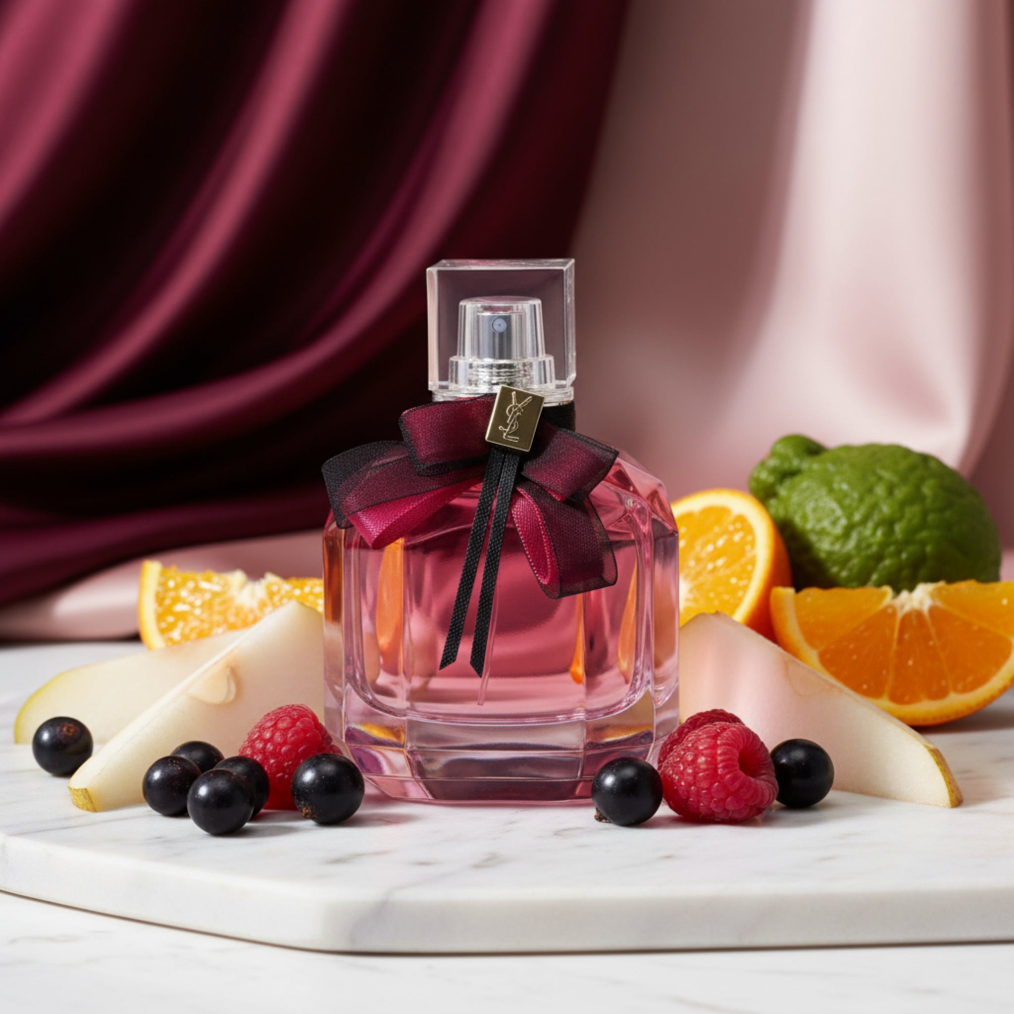 Pink perfume bottle with a bow and Yves Saint Laurent logo on a white background