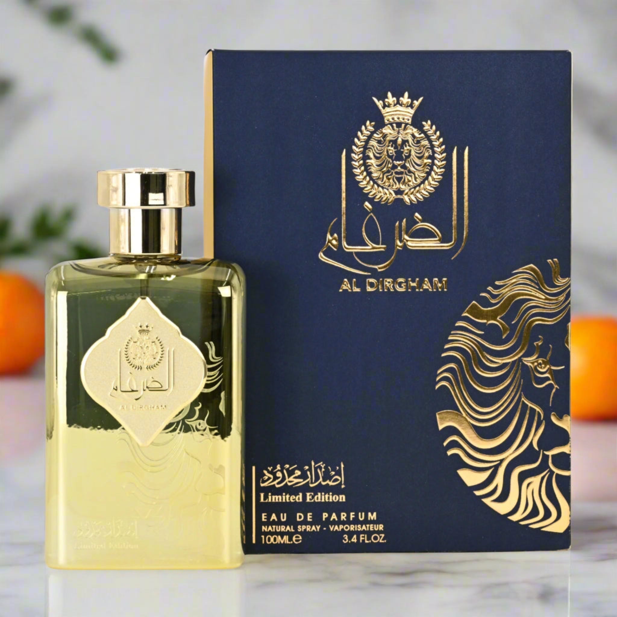 Gold and black Al Dingham perfume bottle and packaging on a marble surface with oranges in the background.