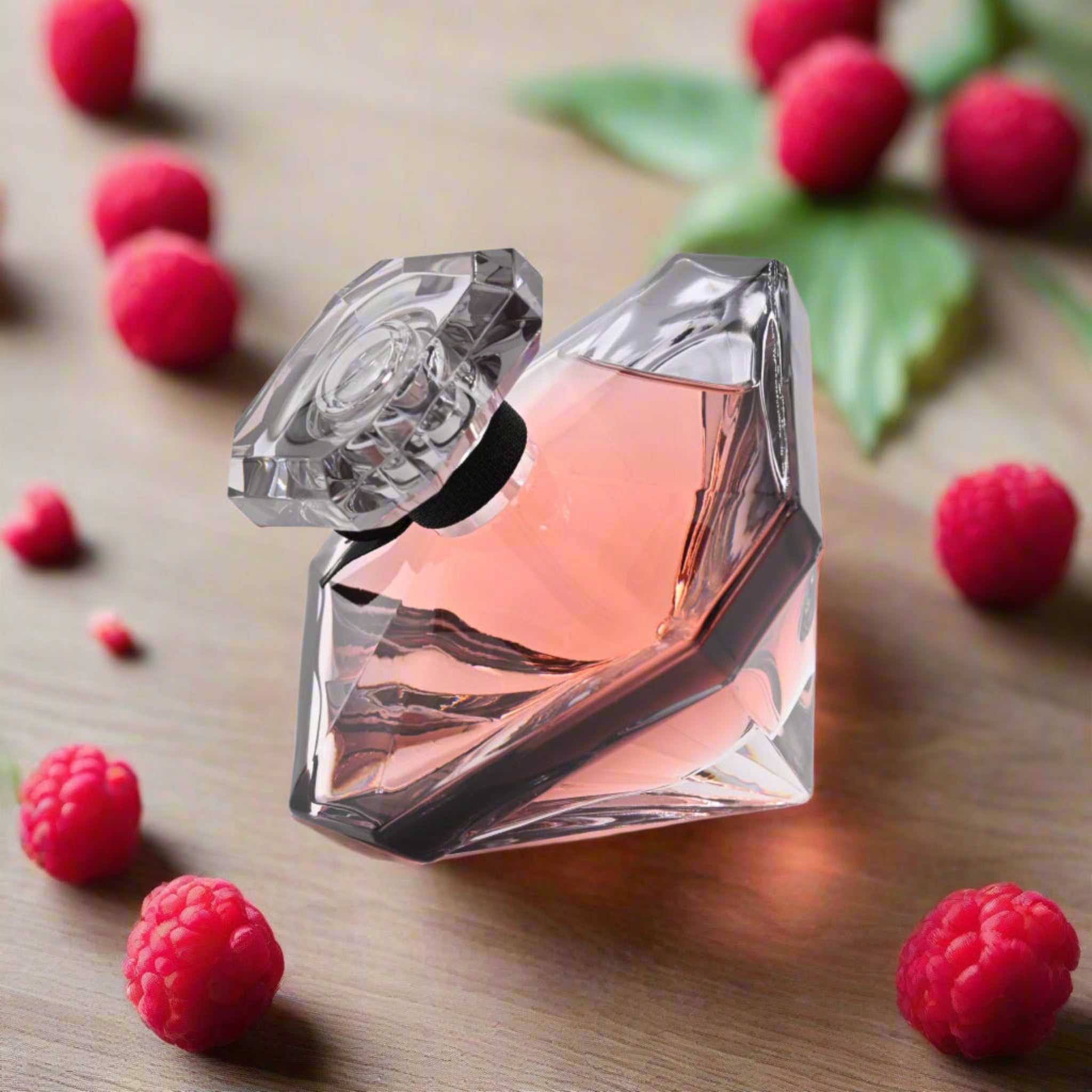 Perfume bottle with a diamond-like design surrounded by raspberries on a wooden surface