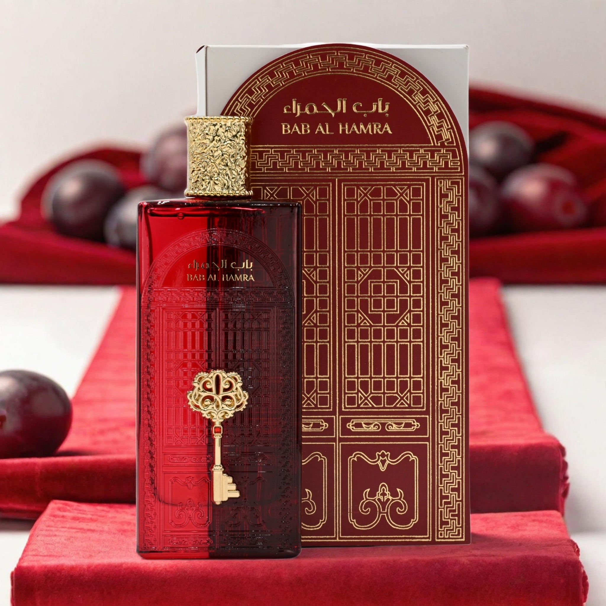 Red and gold perfume bottle with decorative box on a red surface