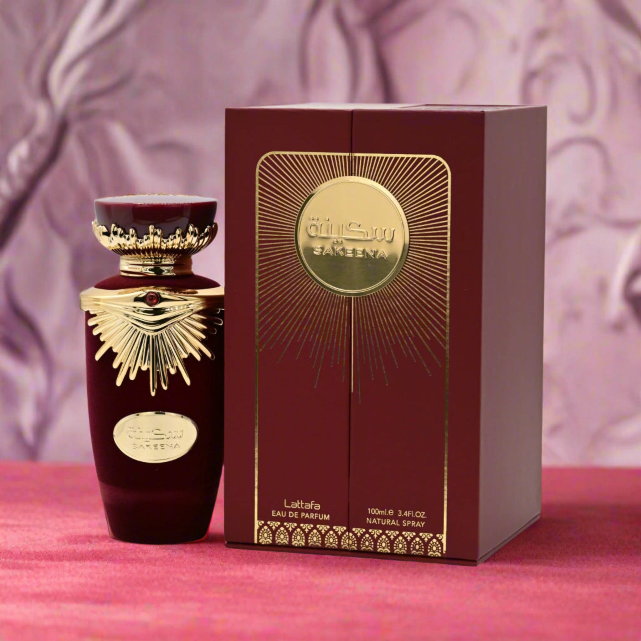 Luxurious red and gold perfume bottle with matching box on a pink surface