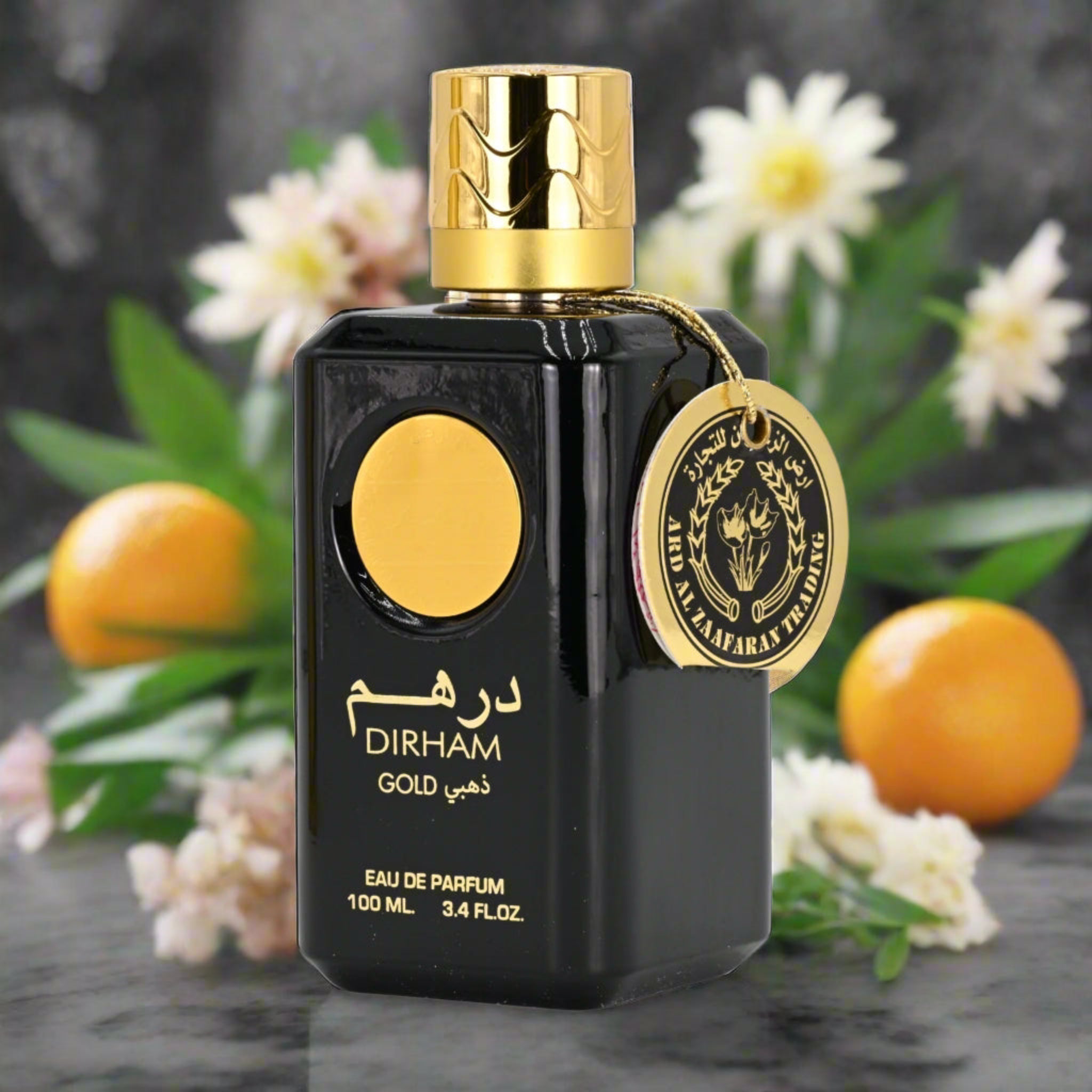 Black and gold Dirham Gold perfume bottle with oranges and flowers in the background