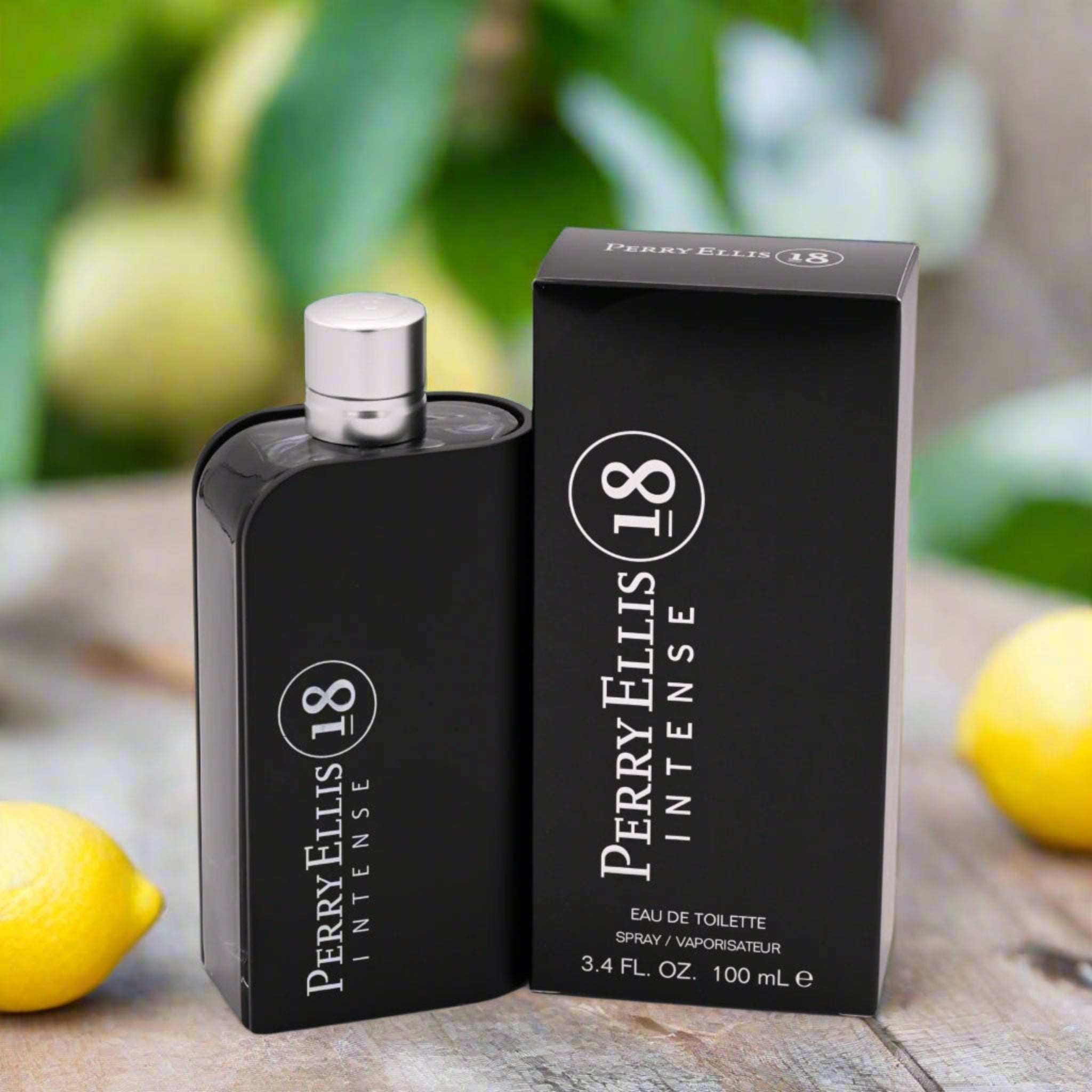 Perry Ellis 18 Intense perfume bottle and packaging on a wooden surface with lemons and greenery in the background.