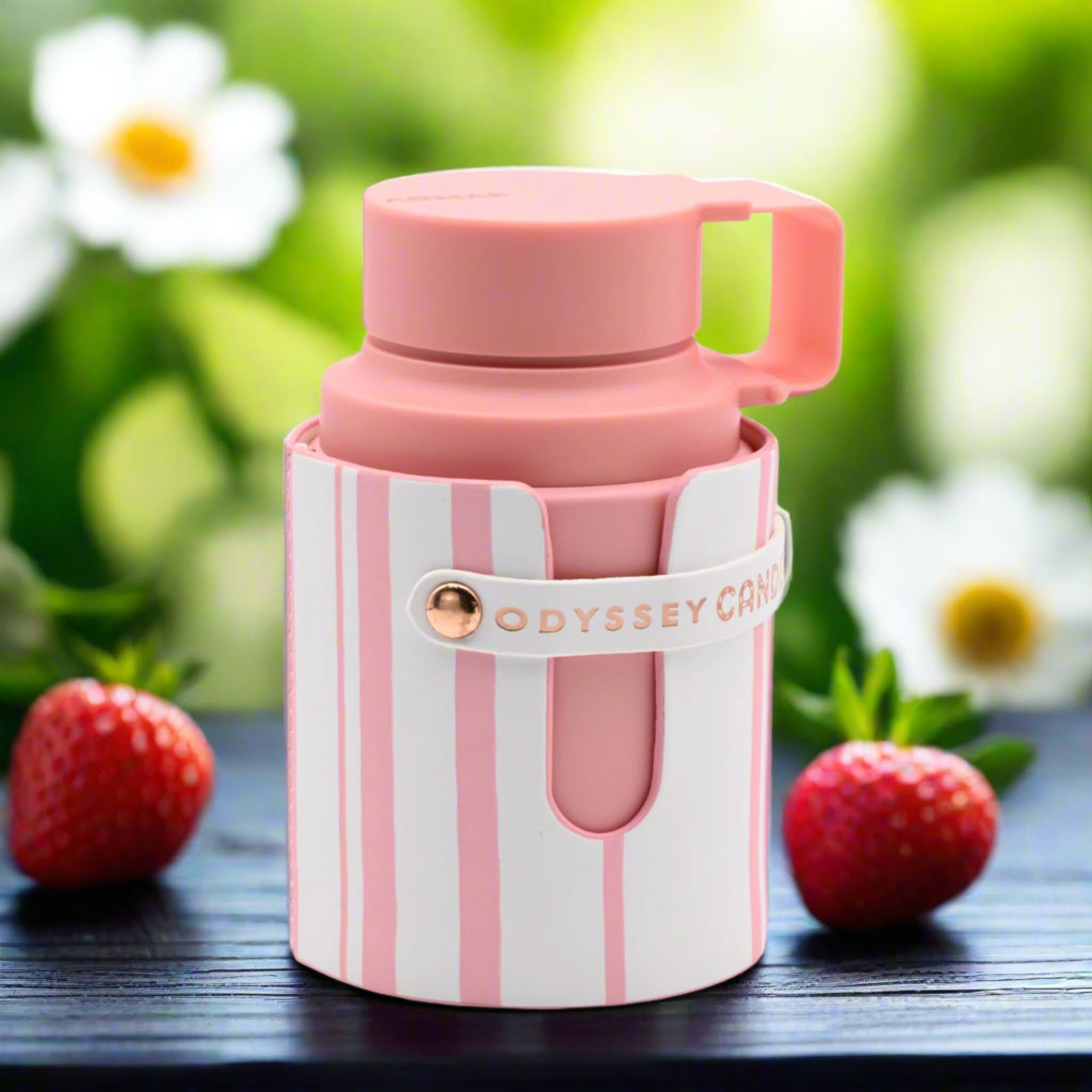 Pink and white striped thermos with a lid on a wooden surface with strawberries and a blurred natural background