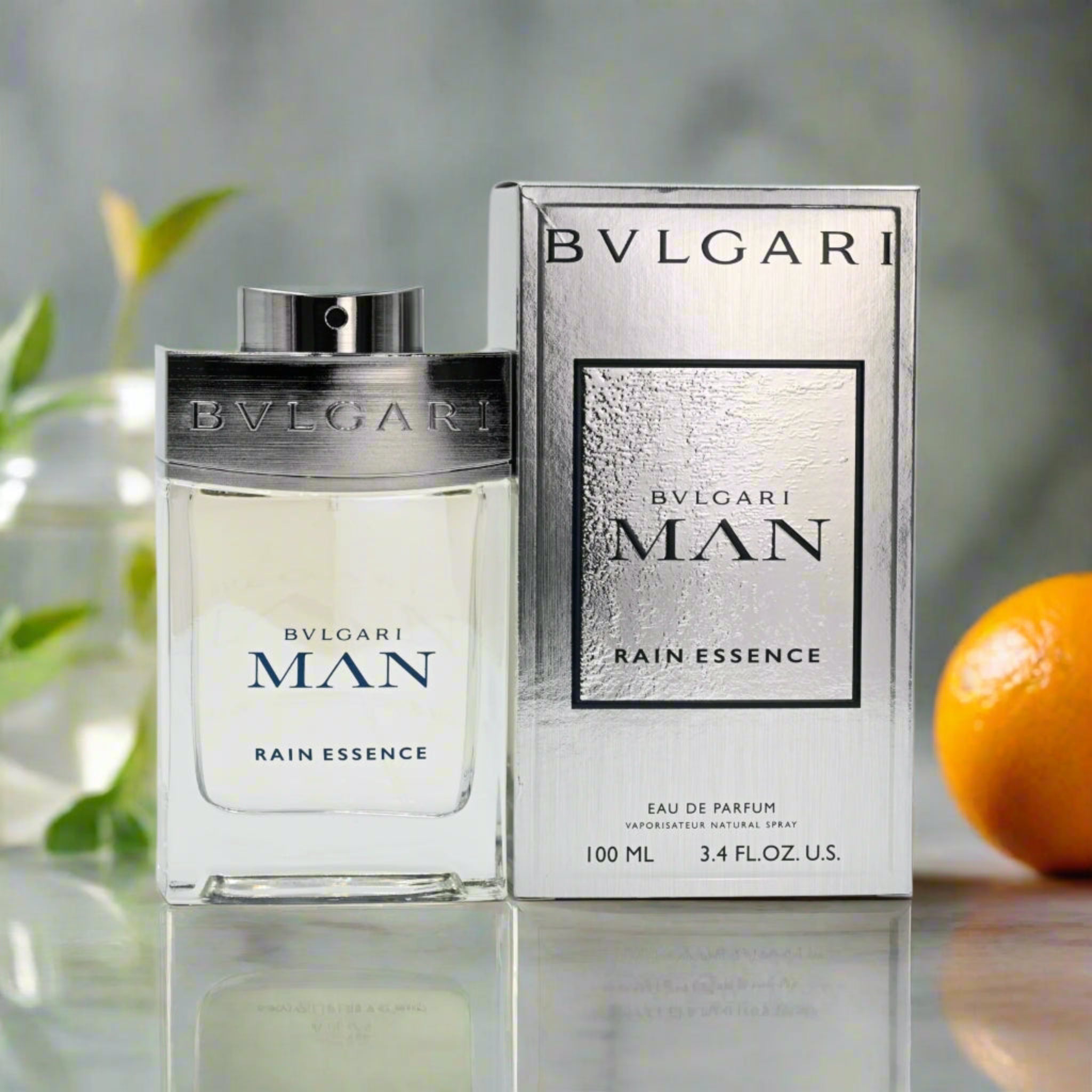 Bvlgari Man Rain Essence perfume bottle and packaging on a reflective surface with a blurred background