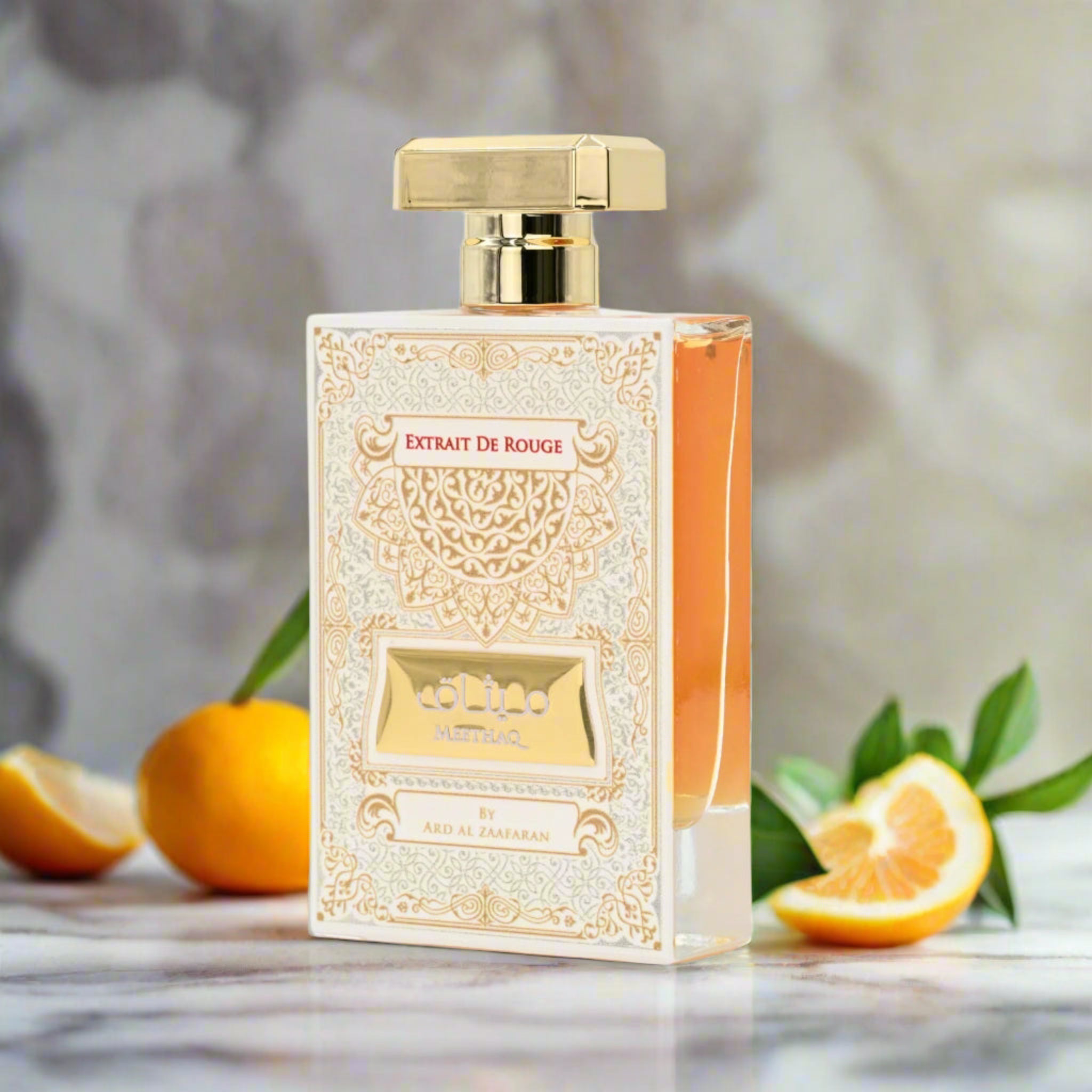 Perfume bottle labeled 'Extrait De Rouge' with oranges and leaves on a marble surface