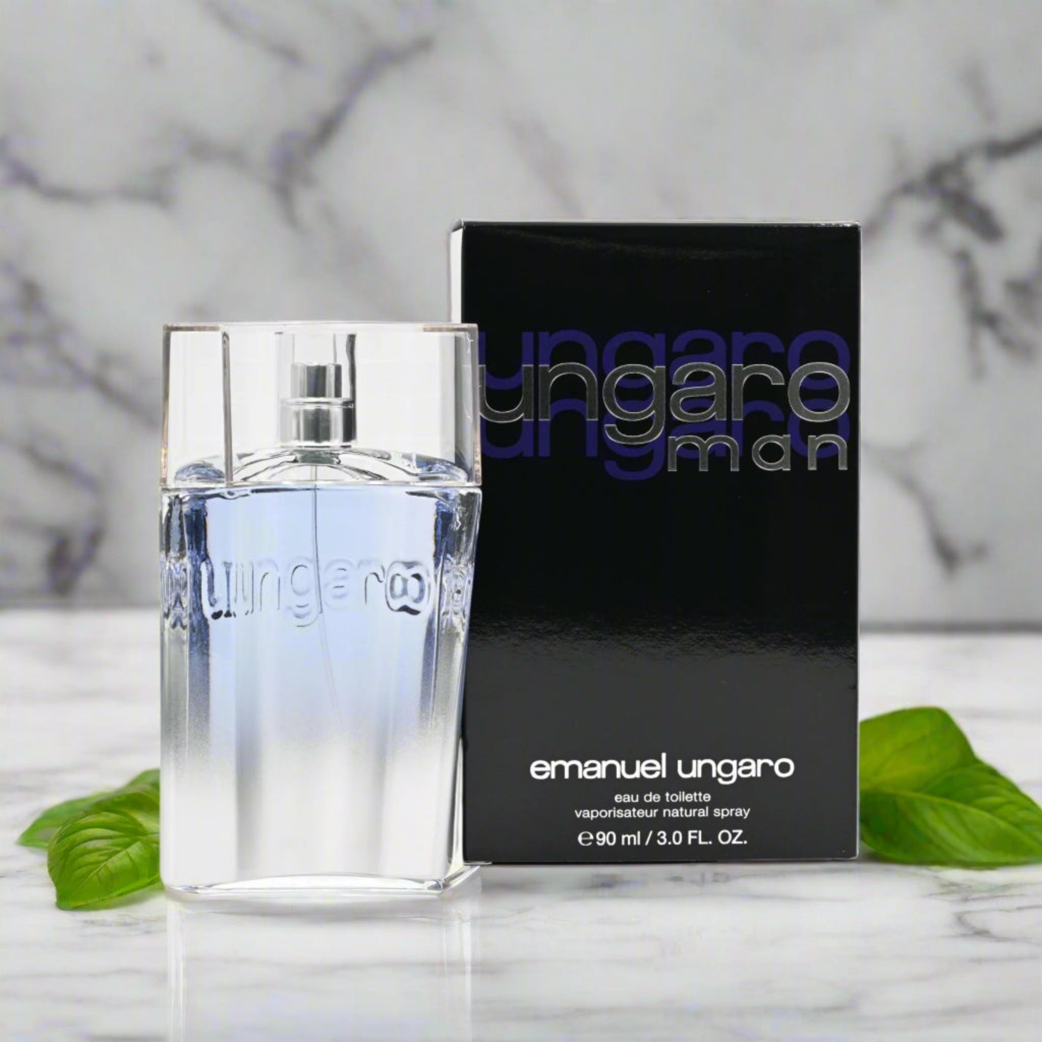 Emanuel Ungaro perfume bottle and packaging on a marble surface with leaves.