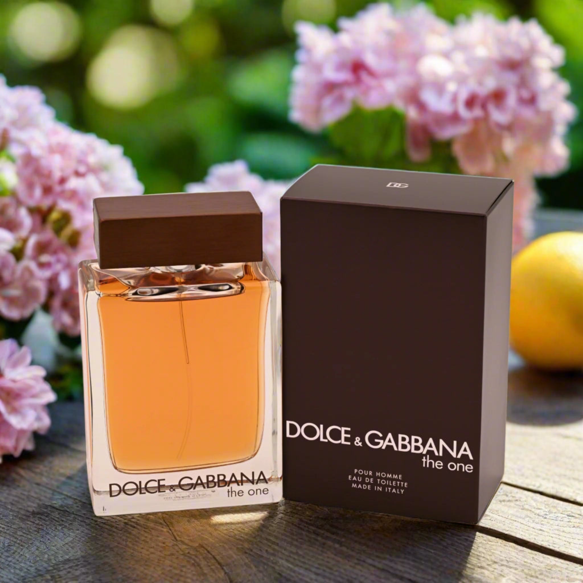Dolce & Gabbana perfume bottle and packaging on a wooden surface with flowers in the background