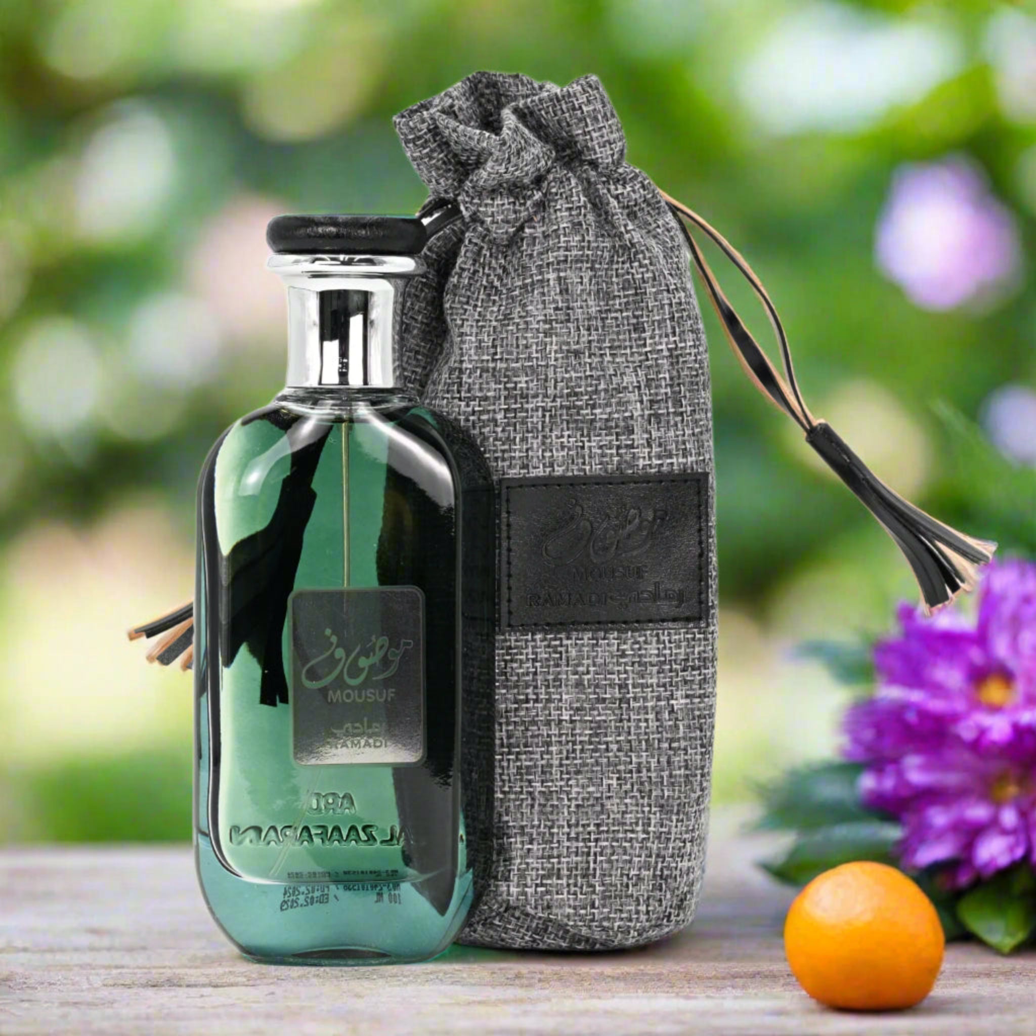 Perfume bottle with a gray drawstring bag on a wooden surface with flowers in the background
