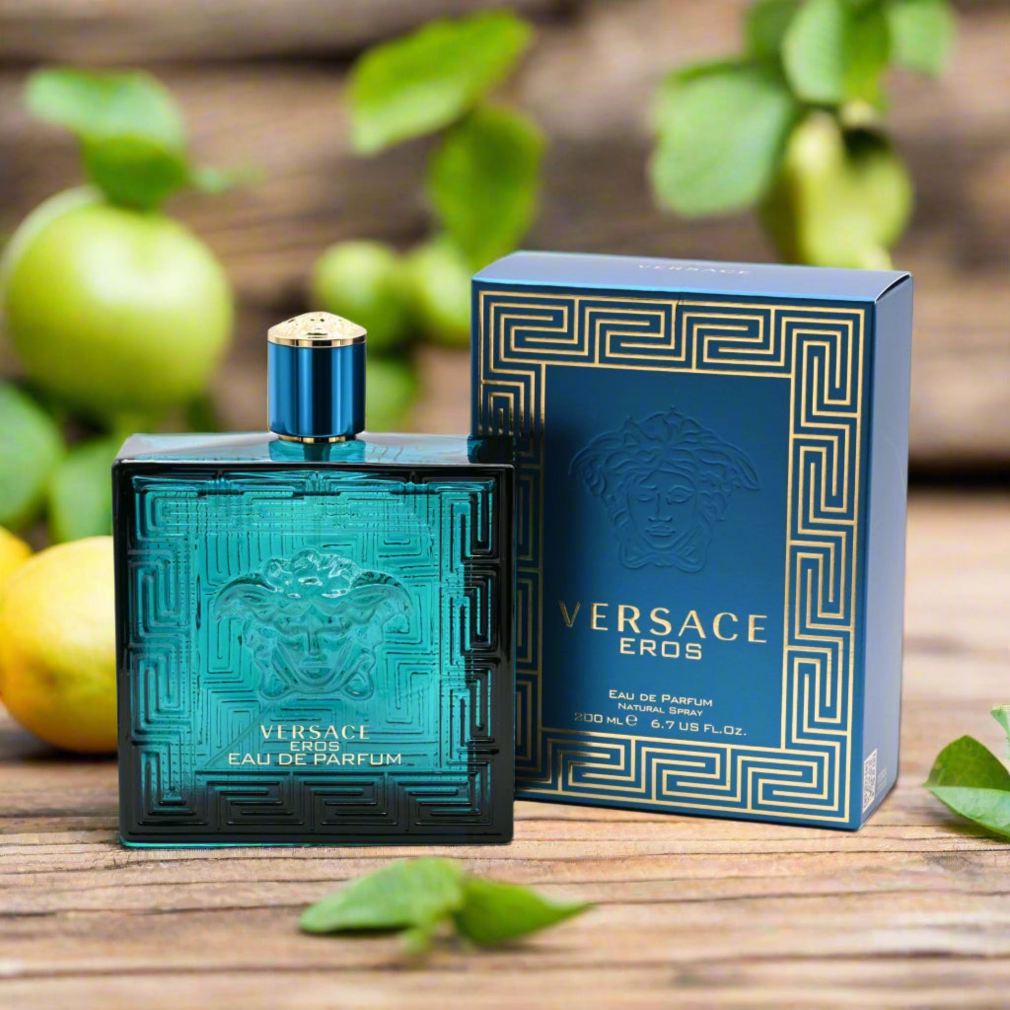 Versace Eros perfume bottle and packaging on a wooden surface with green apples and leaves.