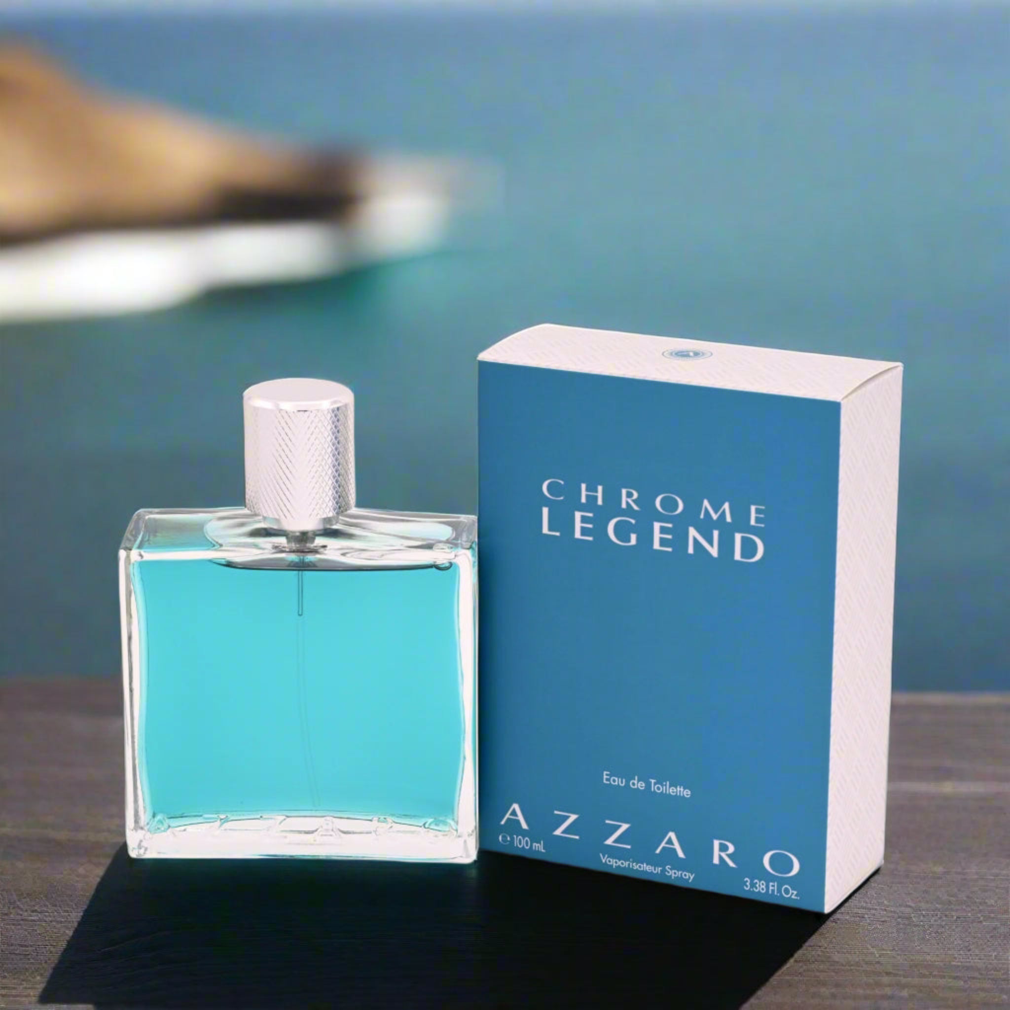 Azzaro Chrome Legend perfume bottle and packaging with a blurred coastal background