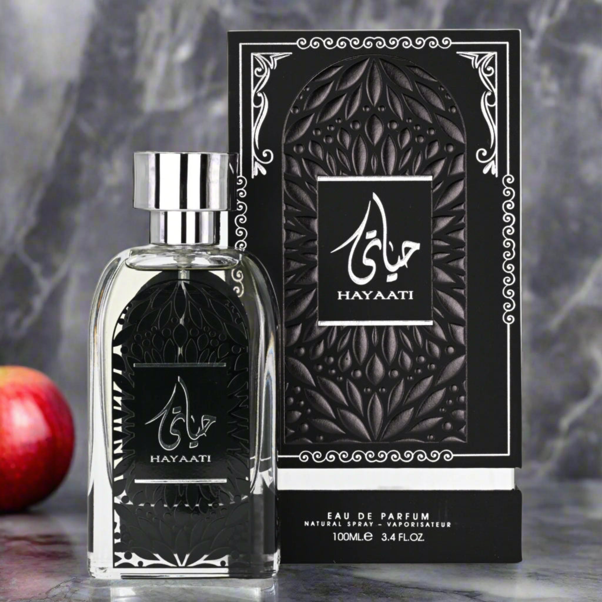 Hayaati perfume bottle and packaging on a marble surface with an apple in the background