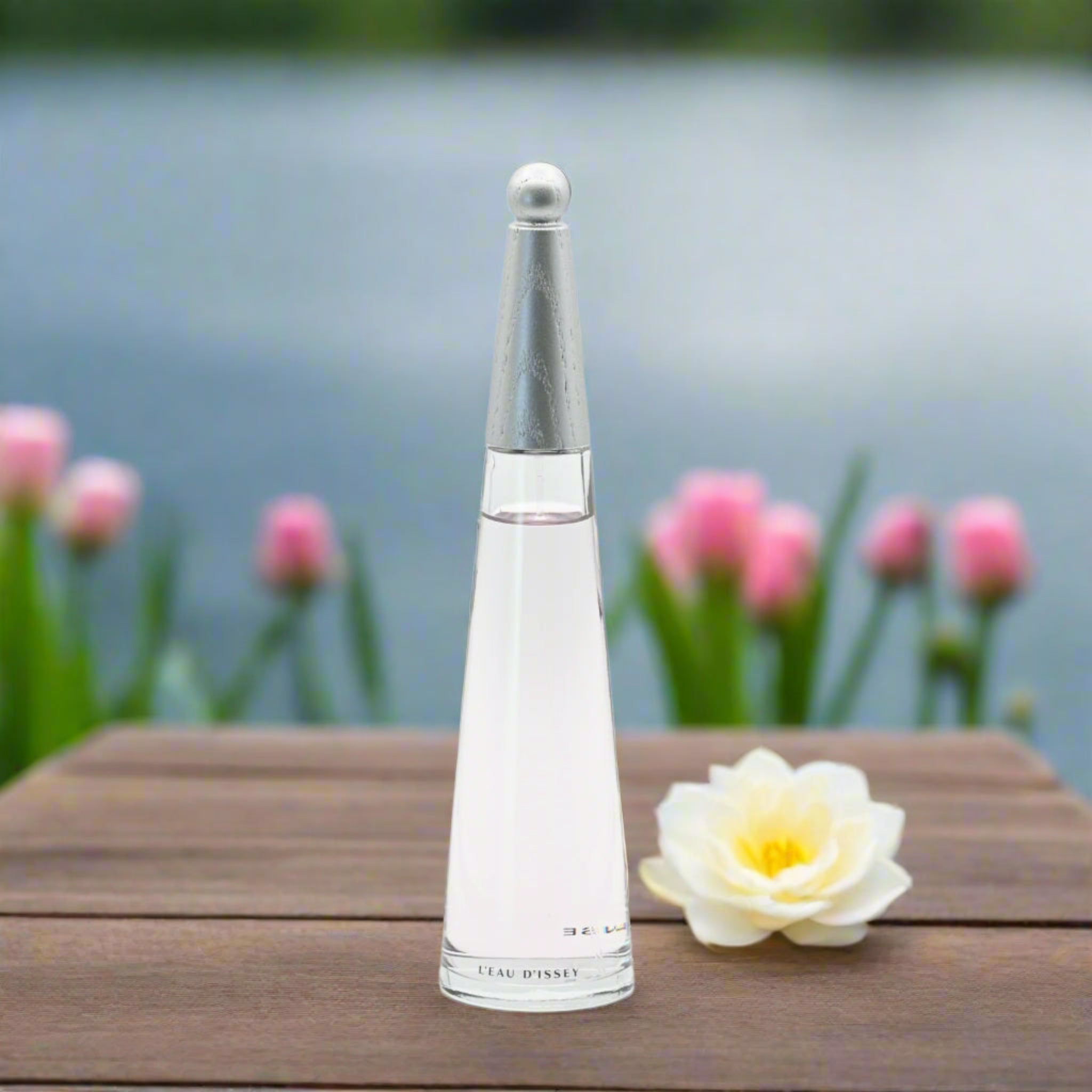Perfume bottle on a wooden surface with flowers in the background