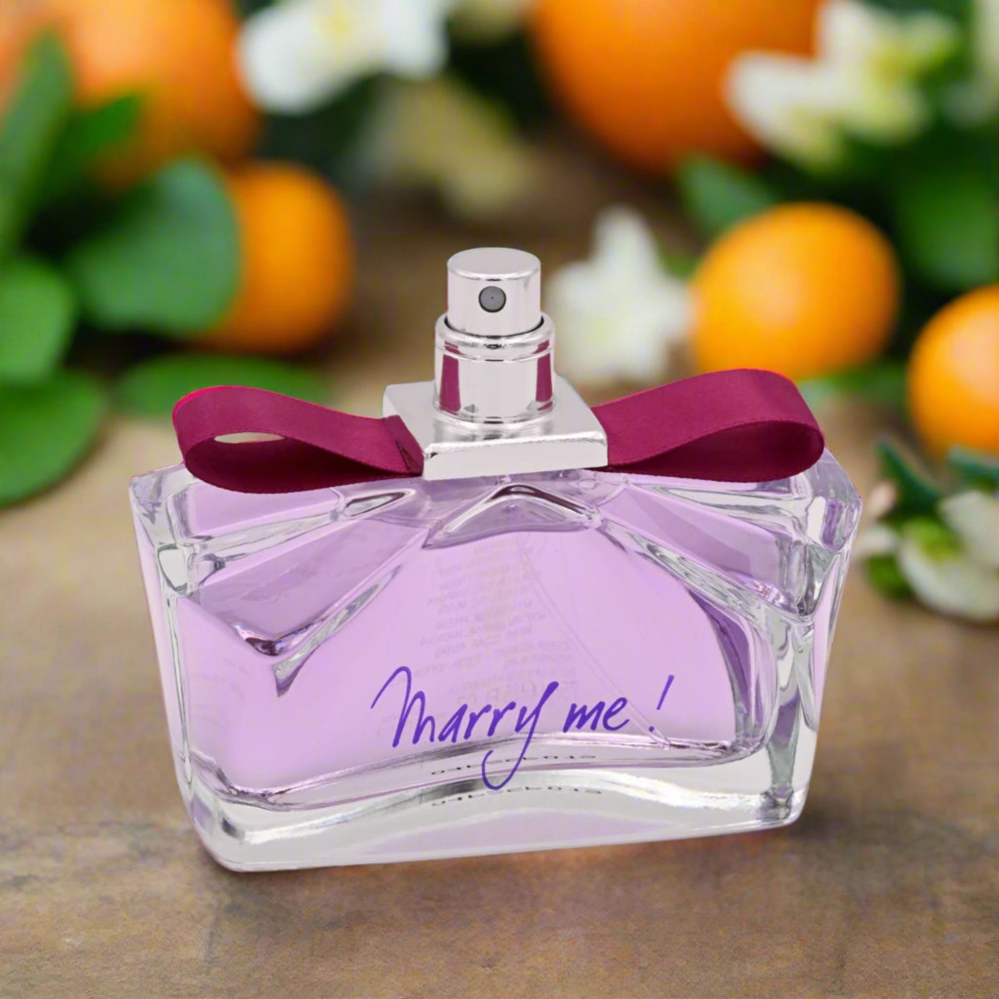 Perfume bottle with pink ribbon and 'Marry me!' text on a white background