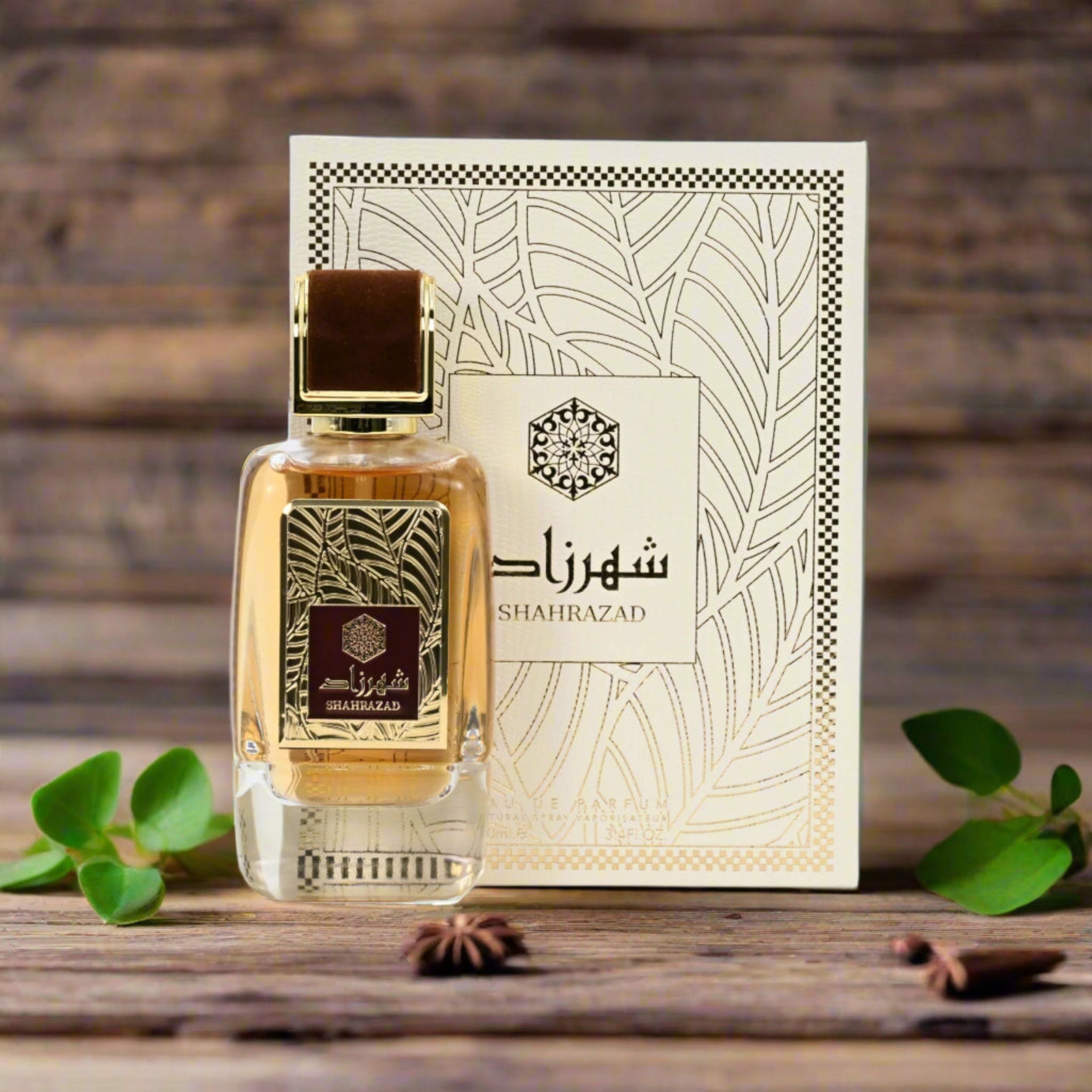 Perfume bottle and packaging with 'Shahrazad' branding on a wooden surface with leaves and star anise.