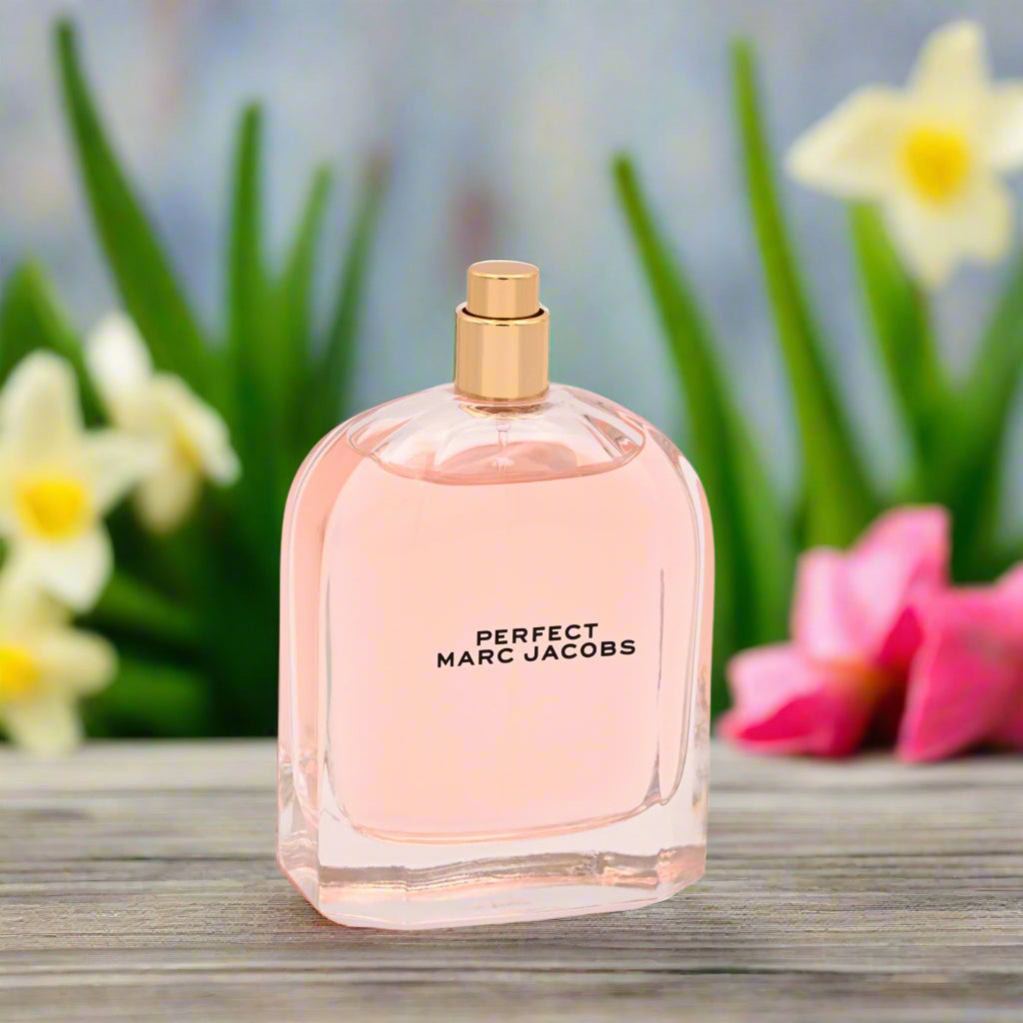 Pink Marc Jacobs perfume bottle with flowers in the background
