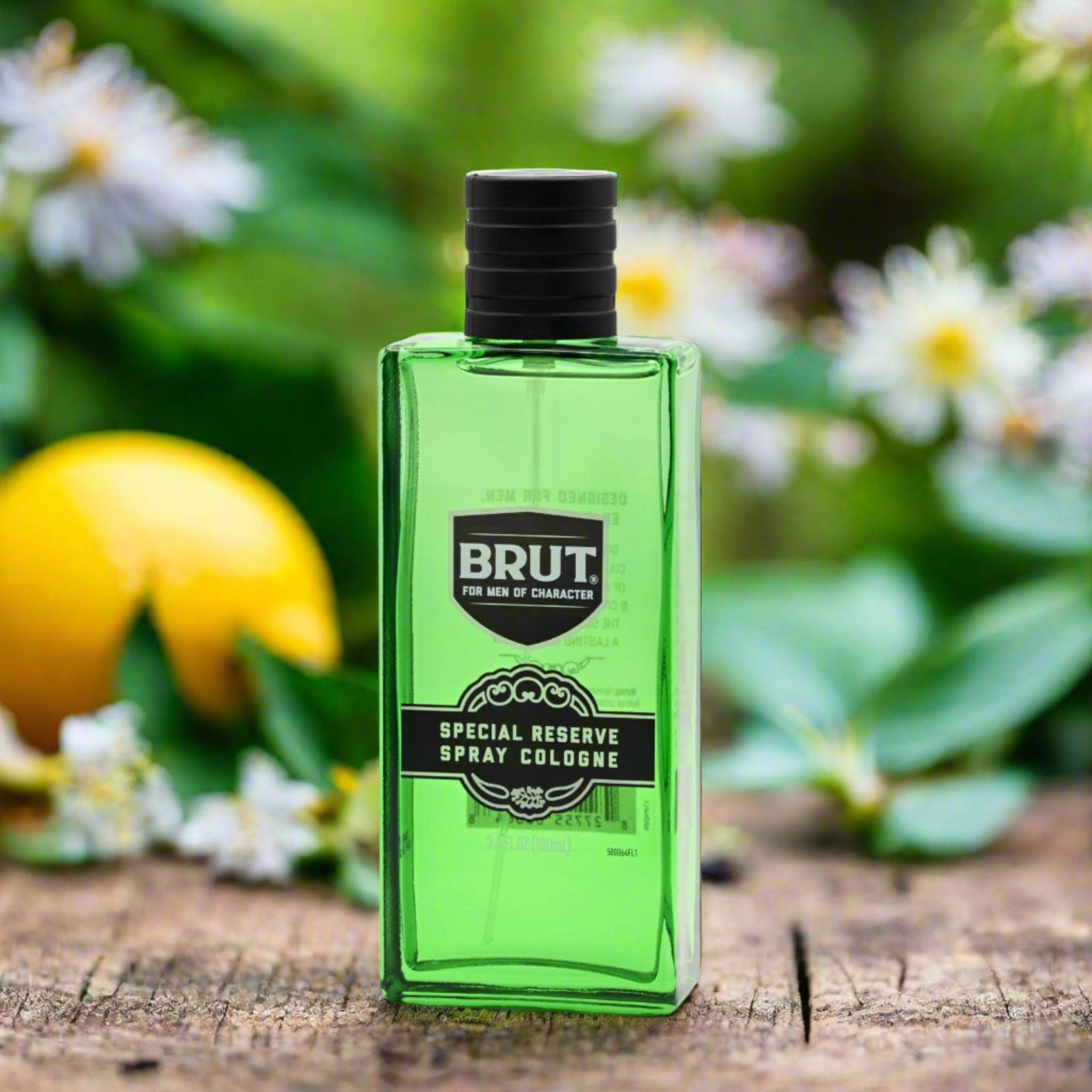 Green Brut cologne bottle with a lemon and flowers in the background