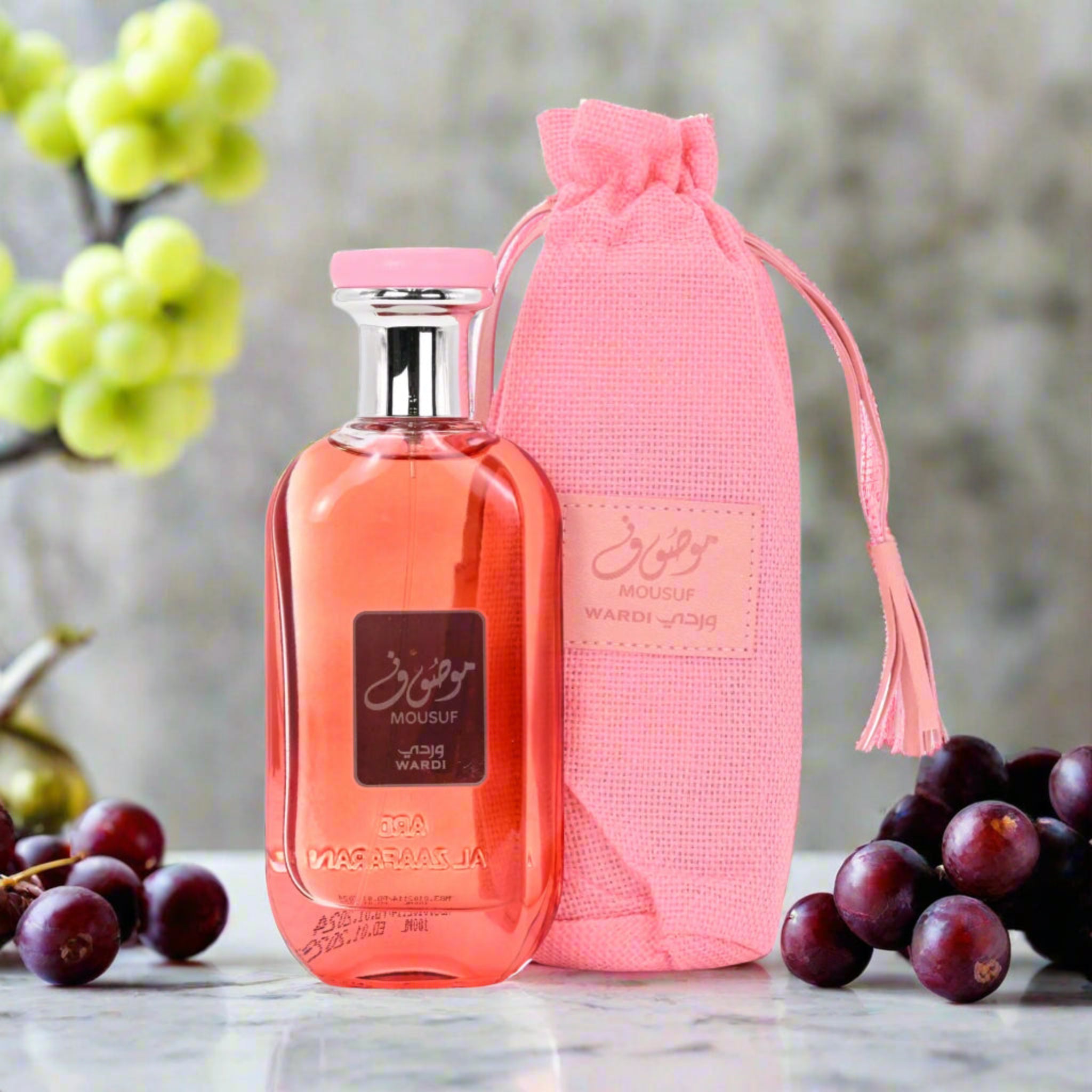 Perfume bottle with pink packaging and grapes in the background