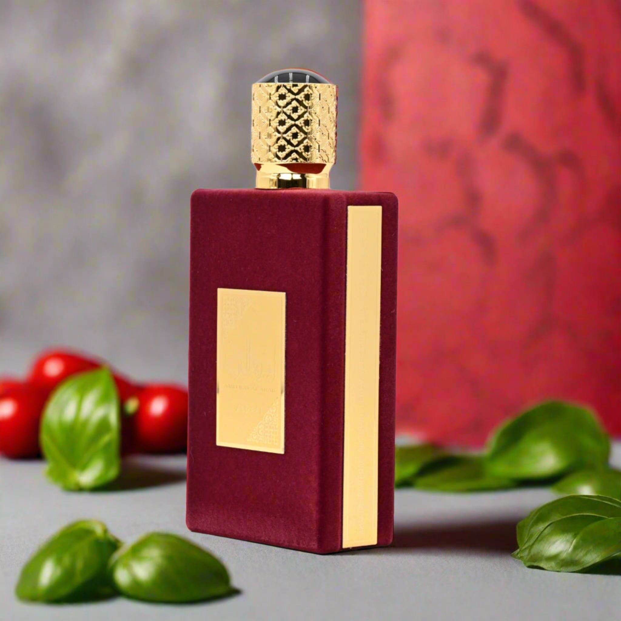 Red and gold perfume bottle with basil leaves in the background
