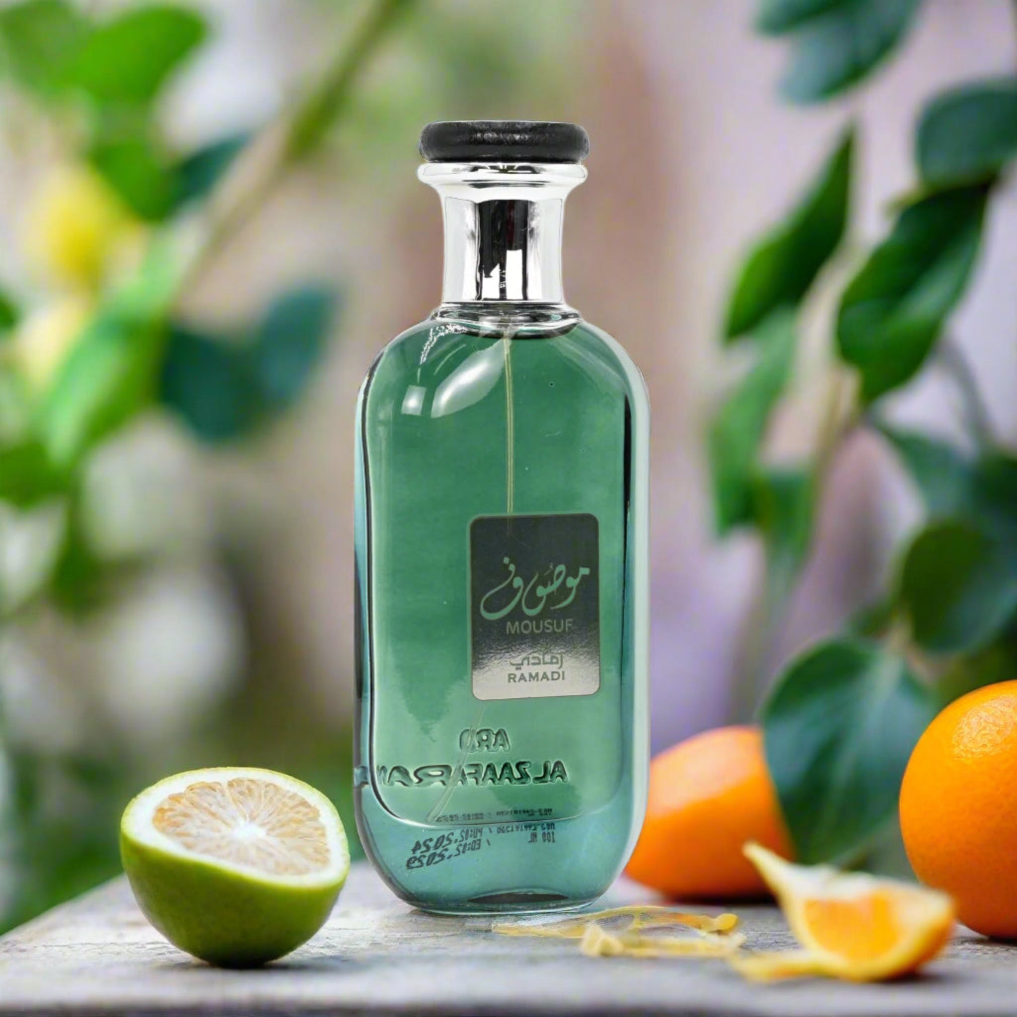 Green perfume bottle with oranges and a lime on a wooden surface