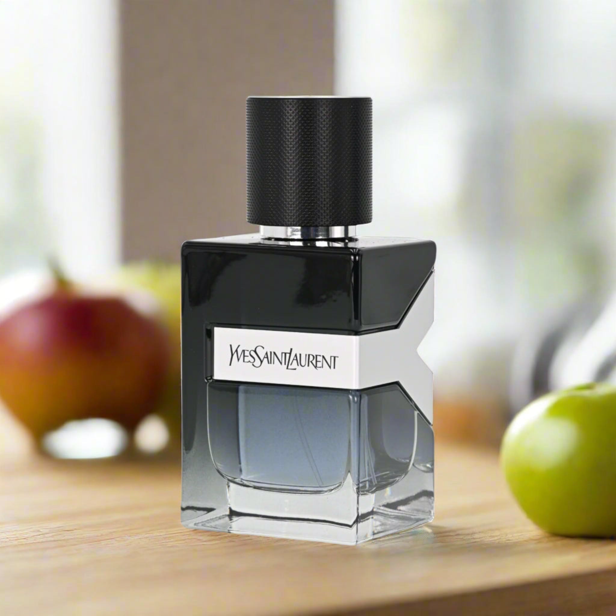 Yves Saint Laurent perfume bottle on a wooden surface with apples in the background