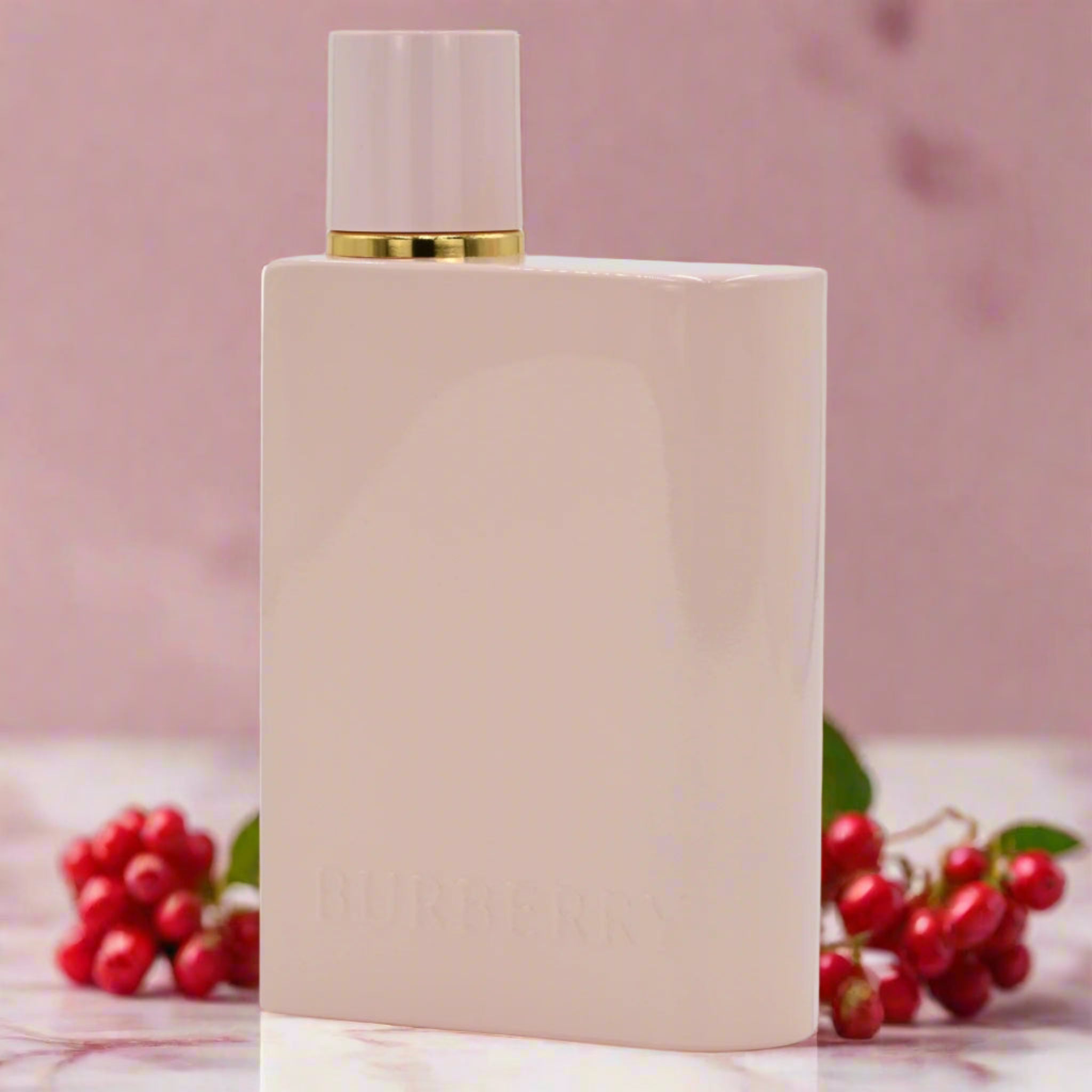 Burberry Her Elixir de Parfum bottle on a marble surface with a blurred floral background.