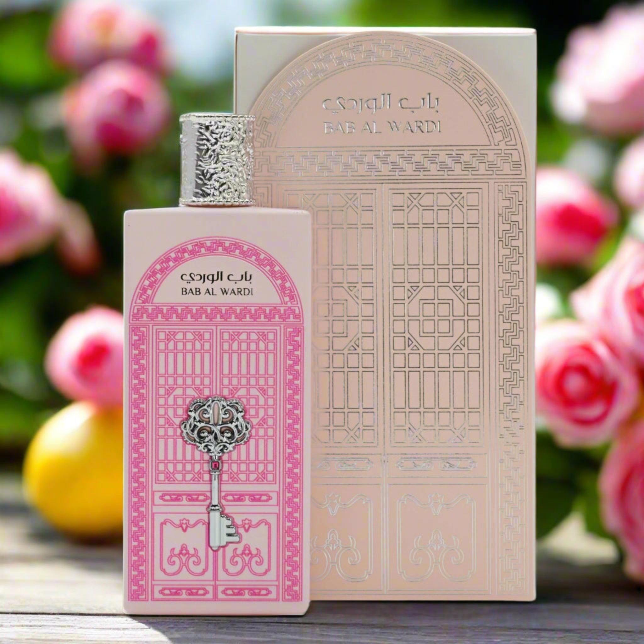 Perfume bottle and packaging with decorative design, set against a blurred floral background