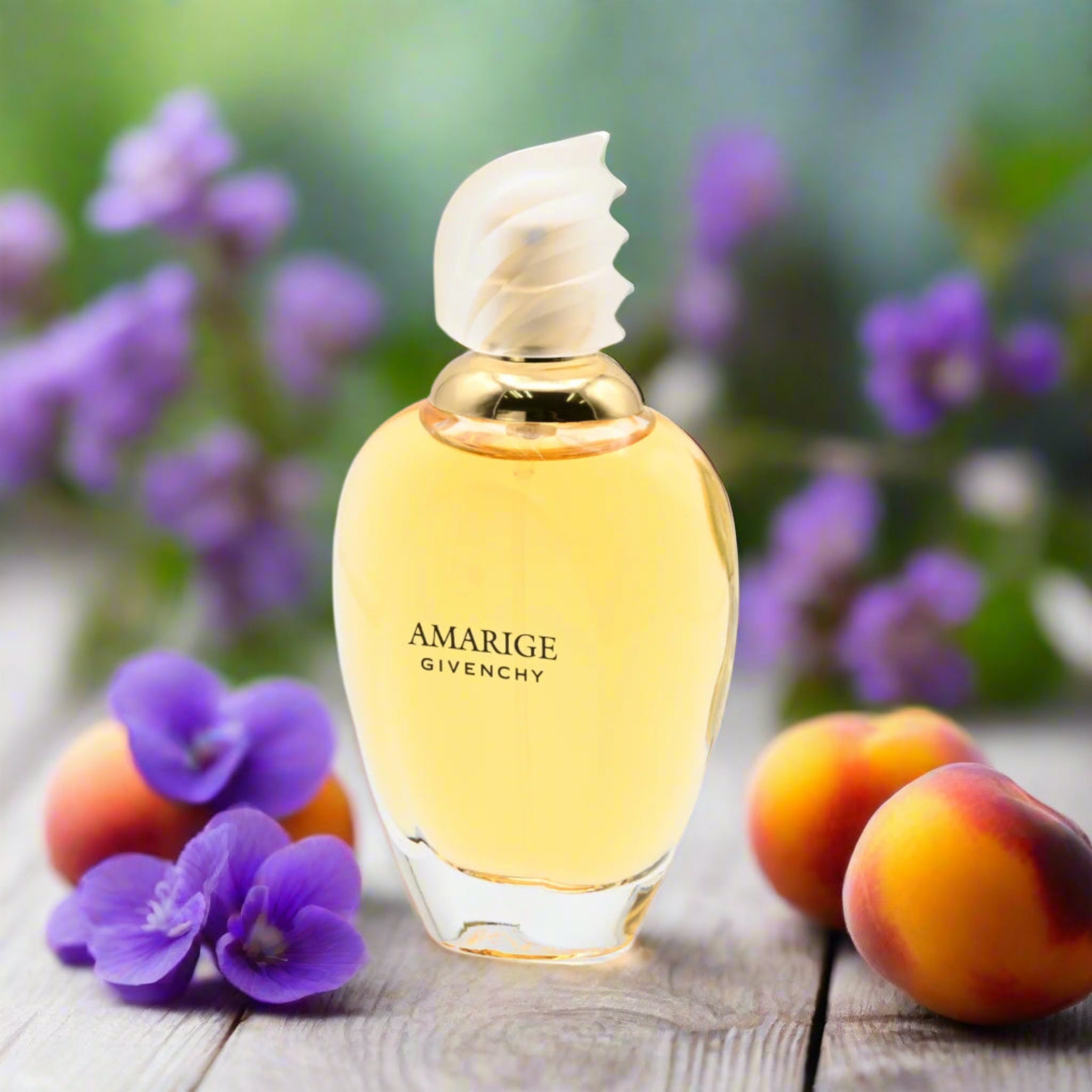 Perfume bottle labeled 'Amarige Givenchy' with peaches and flowers on a wooden surface