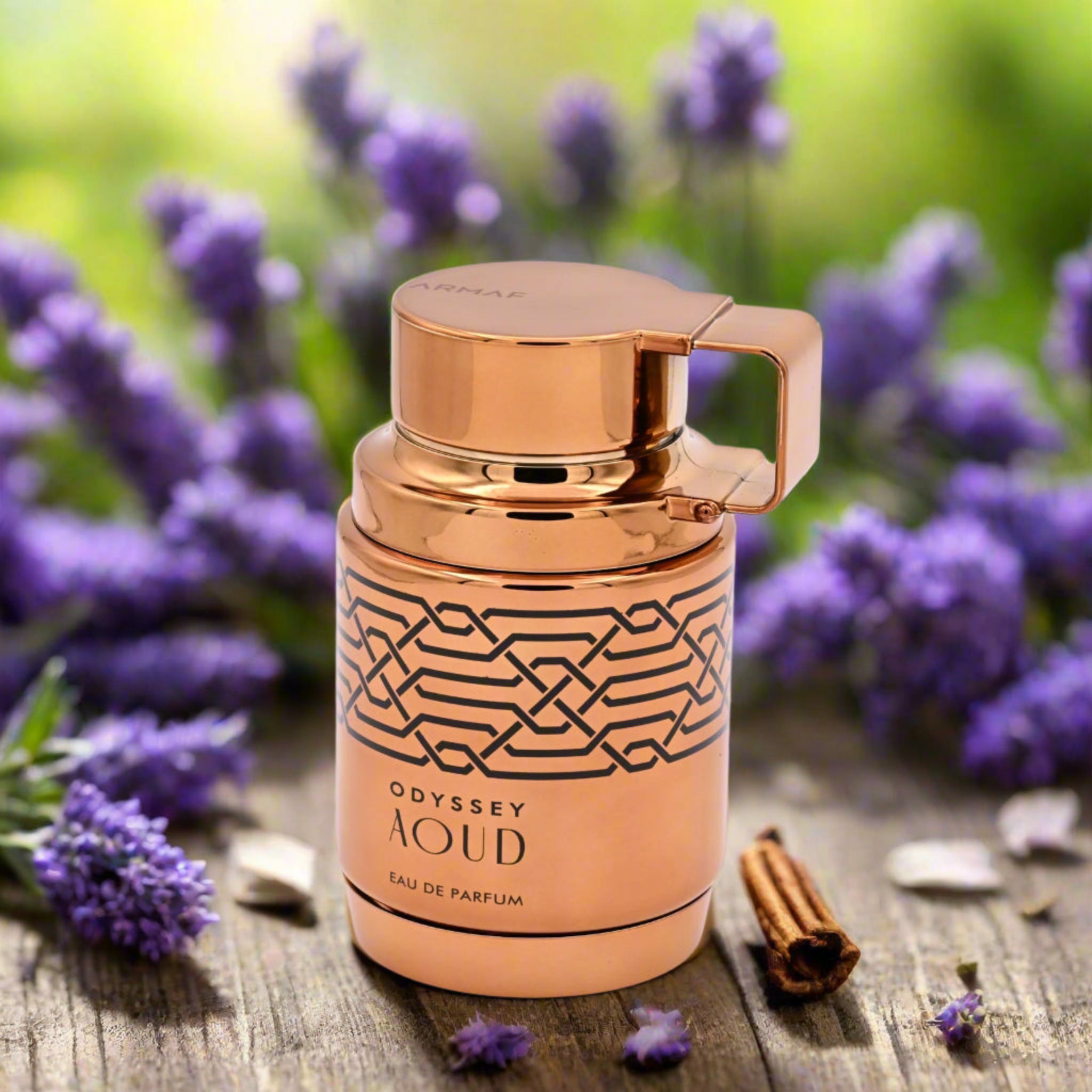 Rose gold Odyssey Aoud perfume bottle with lavender flowers and cinnamon sticks on a wooden surface