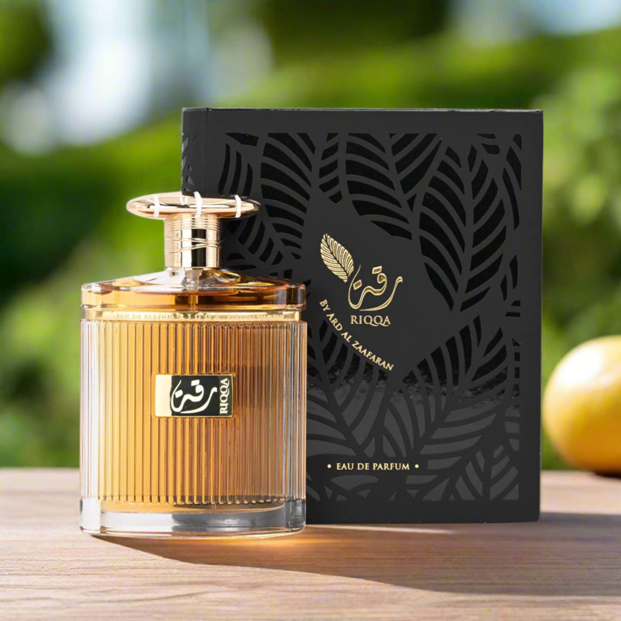 Riqqa perfume bottle and packaging on a wooden surface with a blurred green background