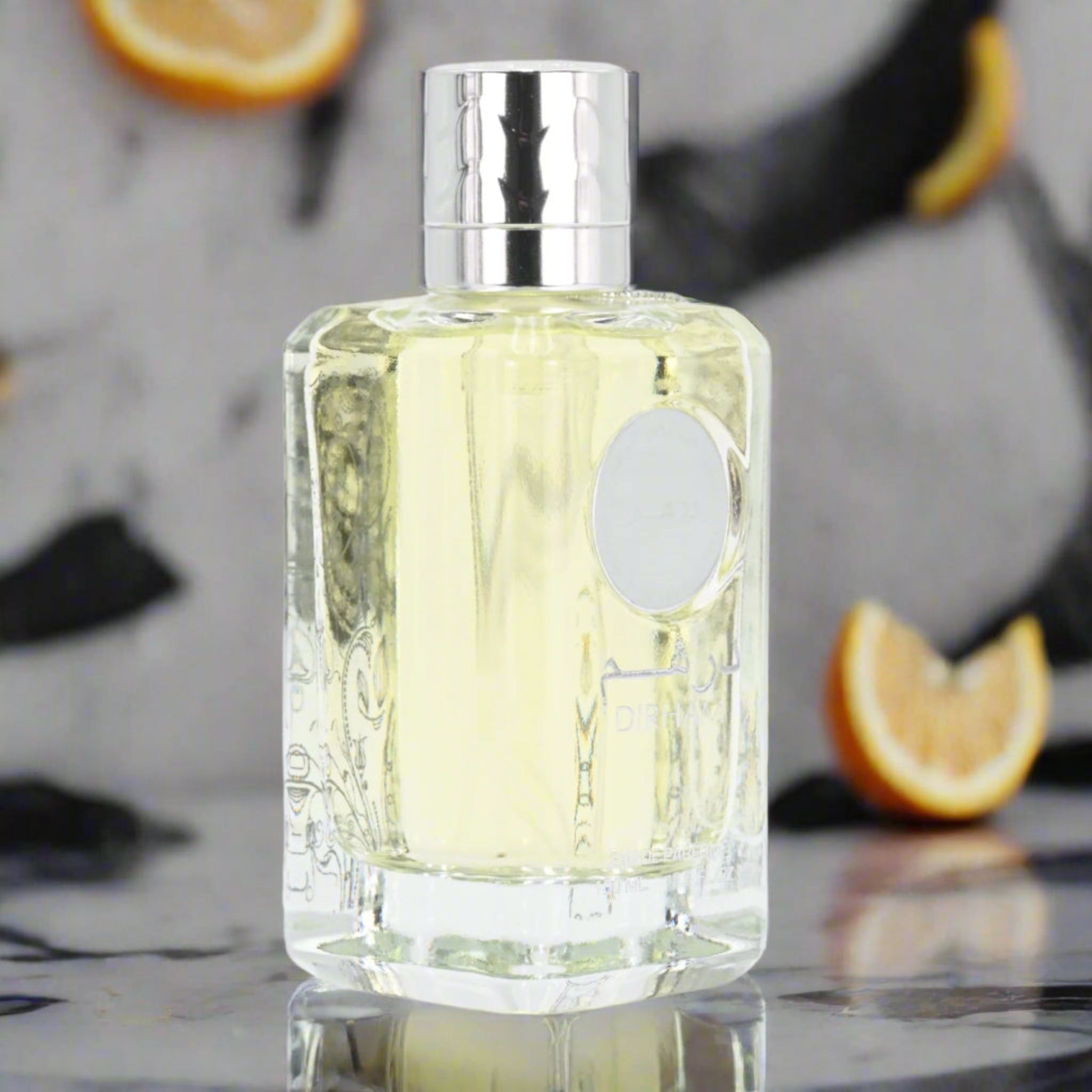 Clear bottle with silver cap on a marble surface with orange slices in the background