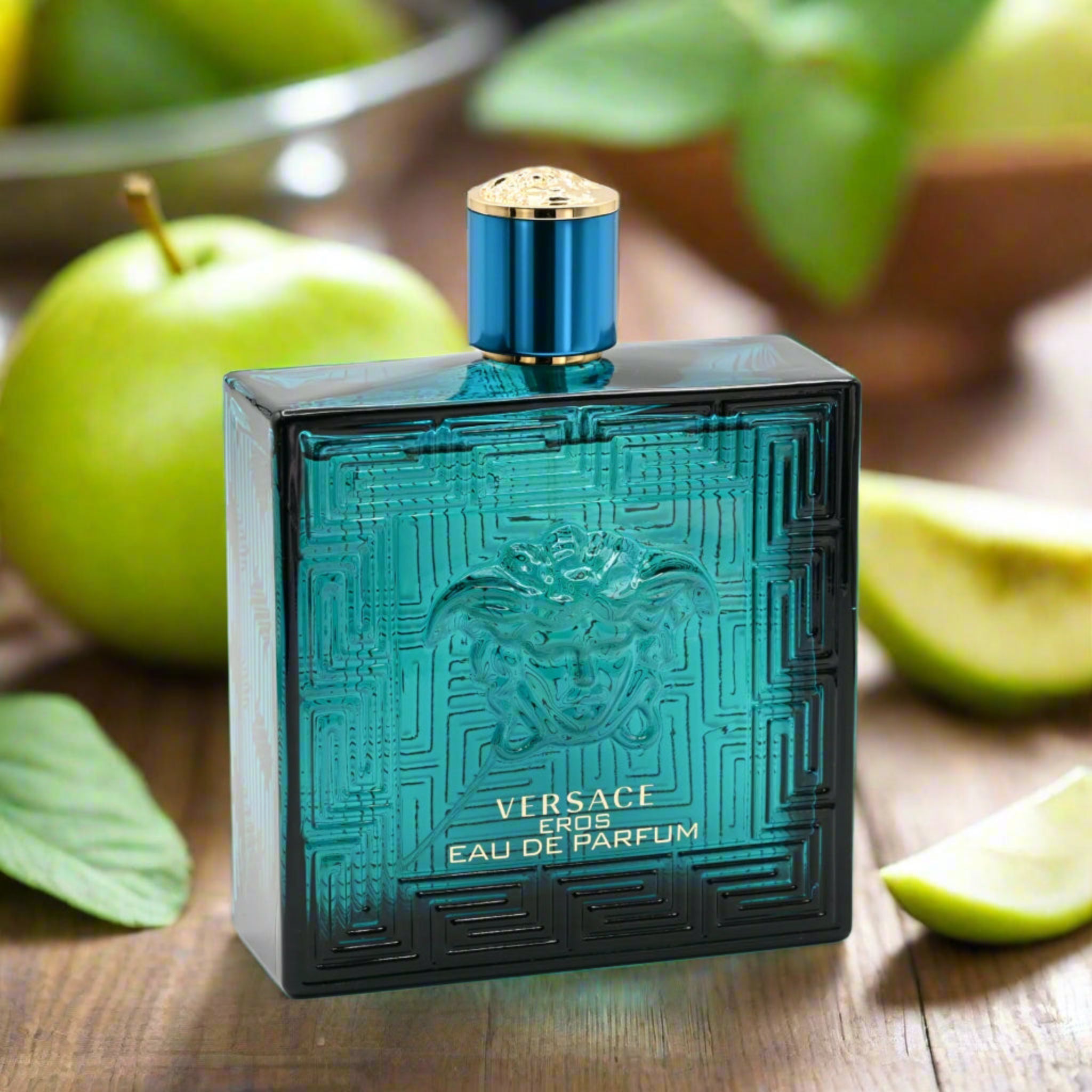 Versace Eros perfume bottle on a wooden surface with green apples in the background