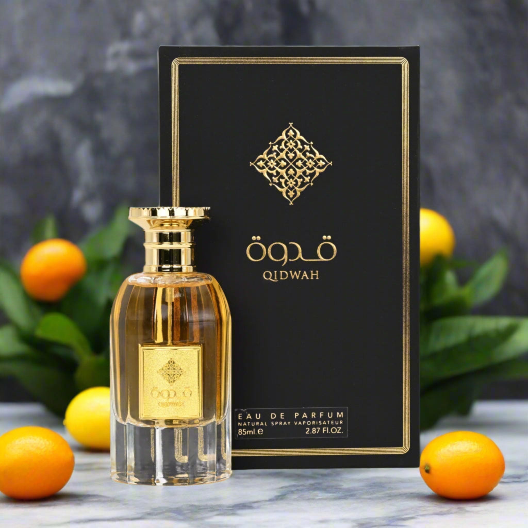 Qidwah eau de parfum bottle and packaging with oranges and leaves on a marble surface.