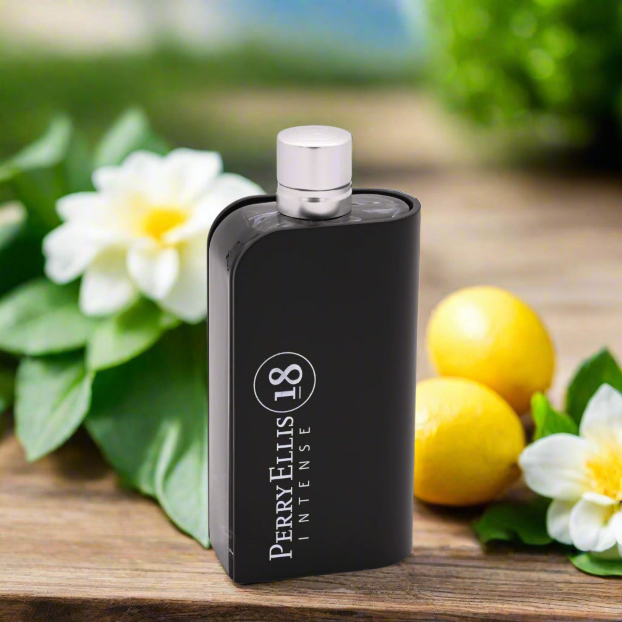 Black Perry Ellis 18 Intense perfume bottle on a wooden surface with flowers and lemons in the background