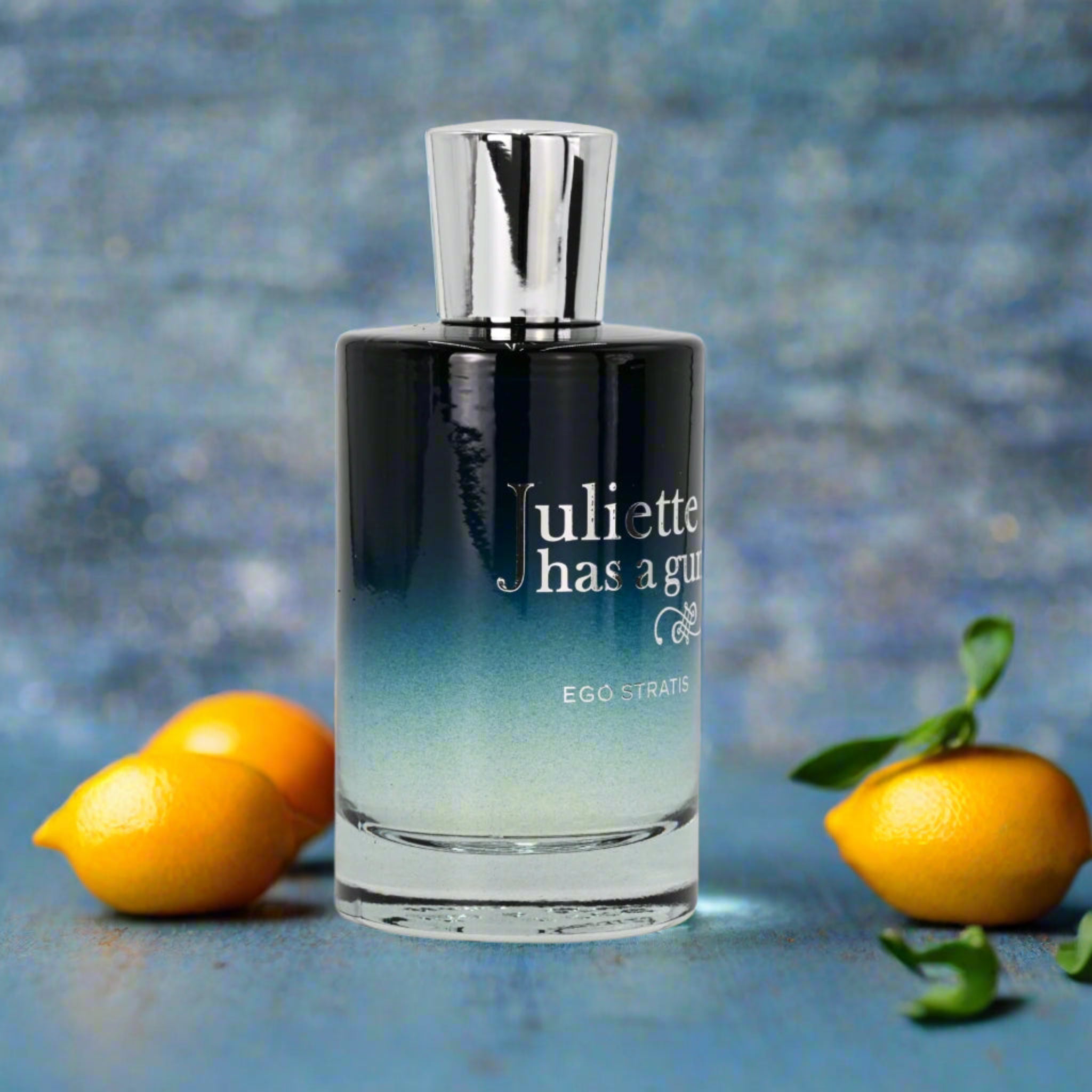 Perfume bottle with 'uliette has a gun' branding next to lemons on a blue background