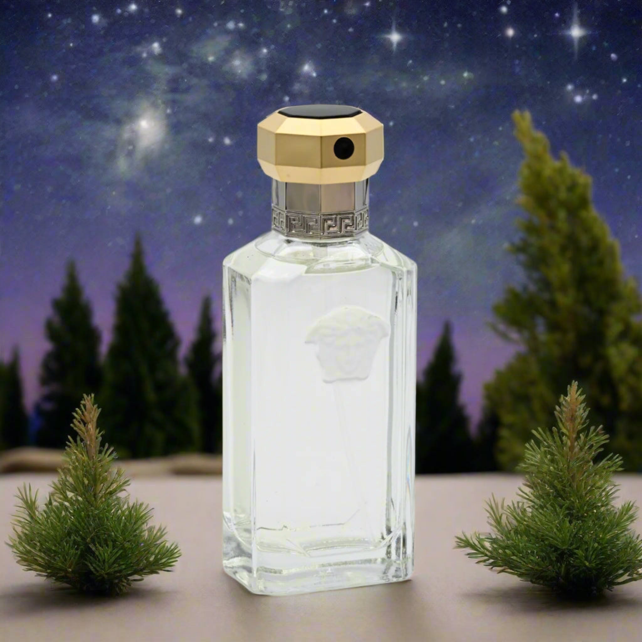 Clear glass perfume bottle with gold cap on a starry night background