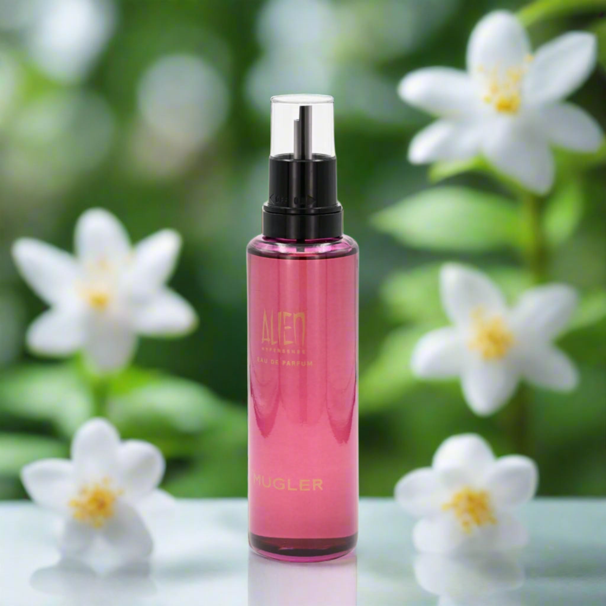 Pink spray bottle with black nozzle on a reflective surface with white flowers in the background