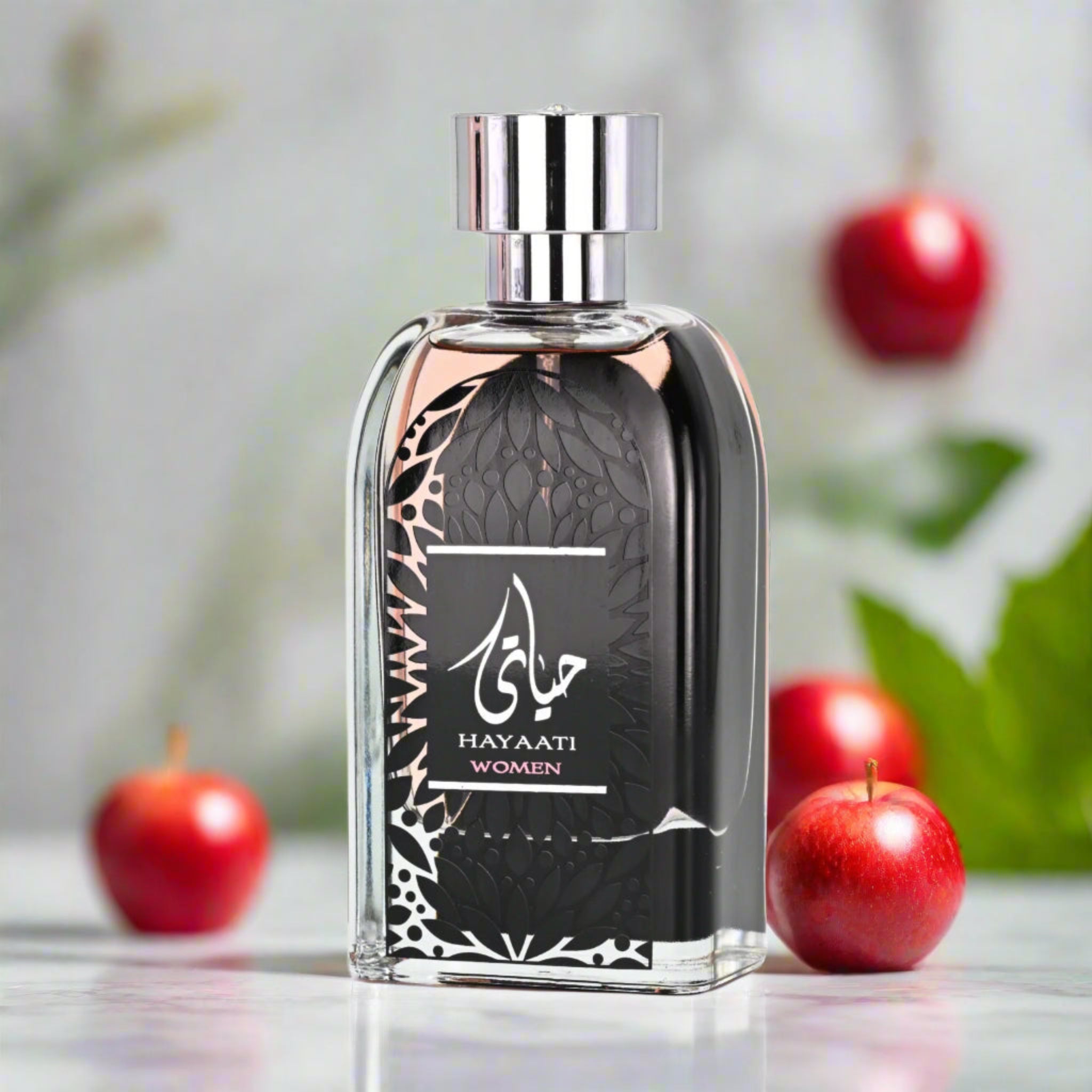 Perfume bottle labeled 'Hayaati Women' with red apples in the background
