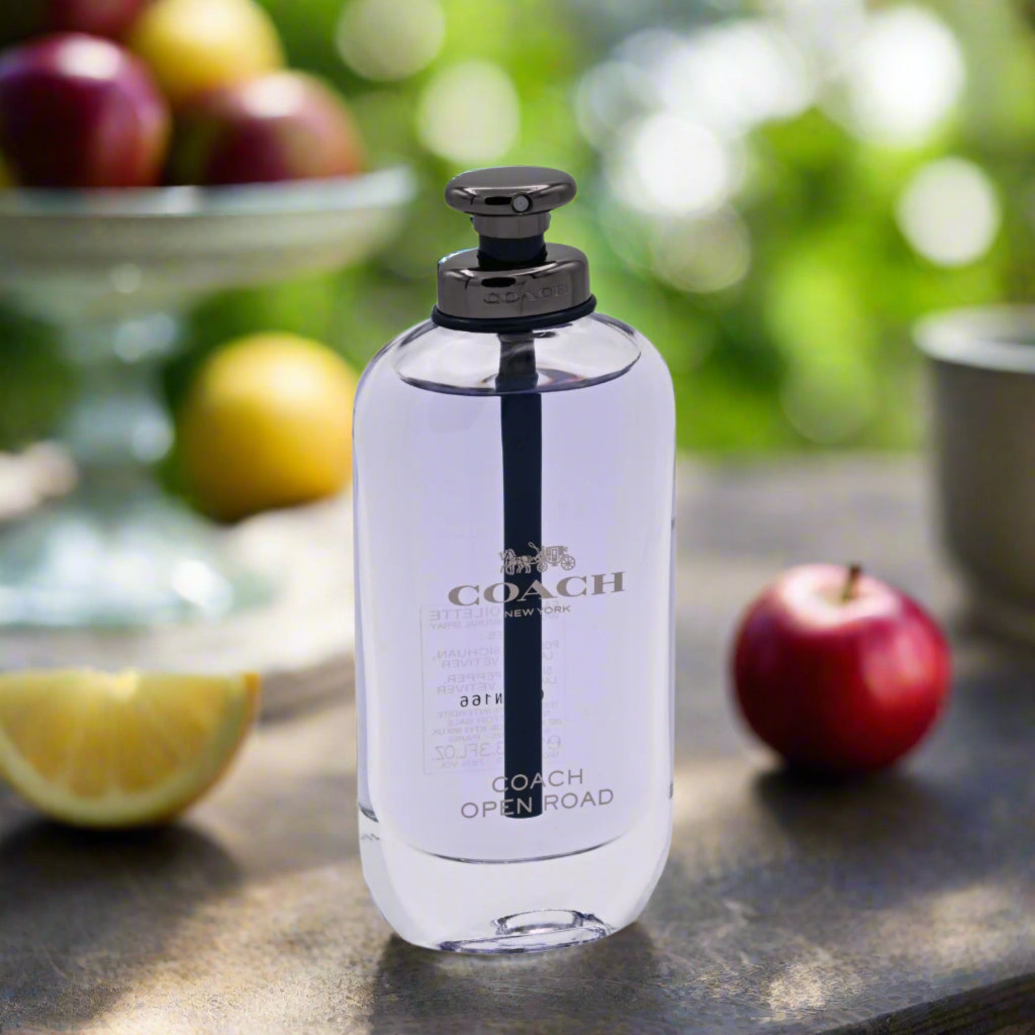 Coach Open Road perfume bottle on a table with fruits in the background