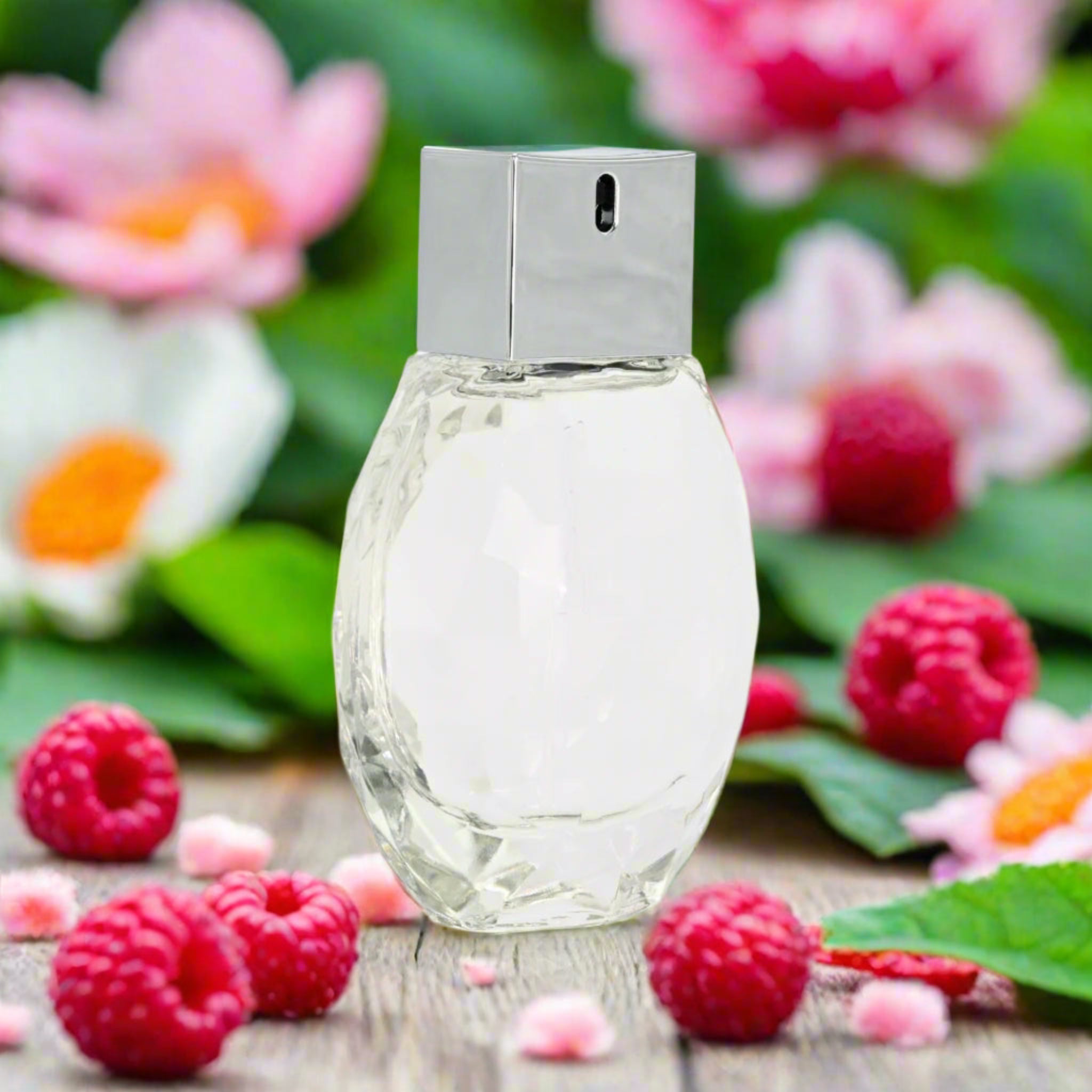 Perfume bottle with raspberries and flowers on a wooden surface