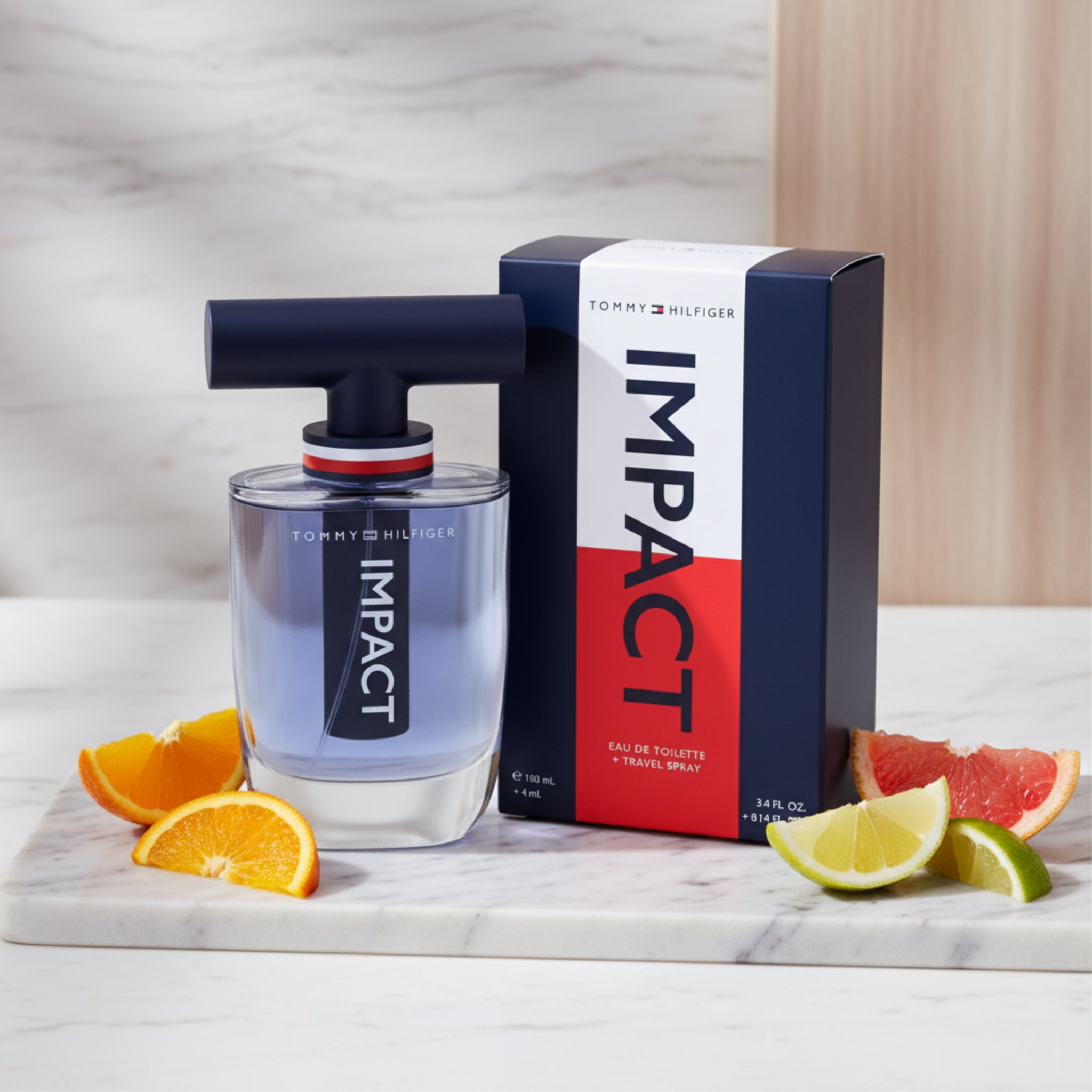 Tommy Hilfiger Impact perfume bottle and packaging on a marble surface with fruit slices.