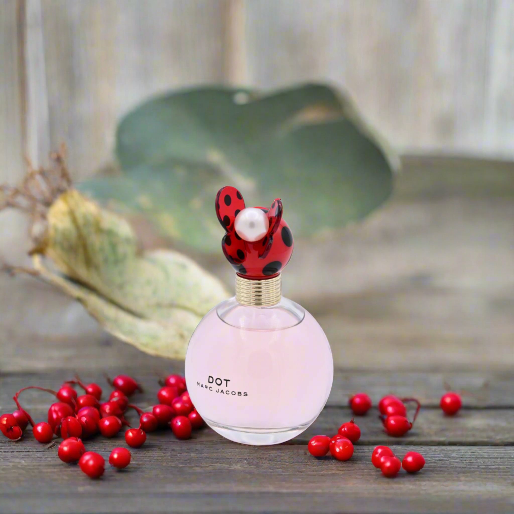 Pink perfume bottle with ladybug design on a wooden background