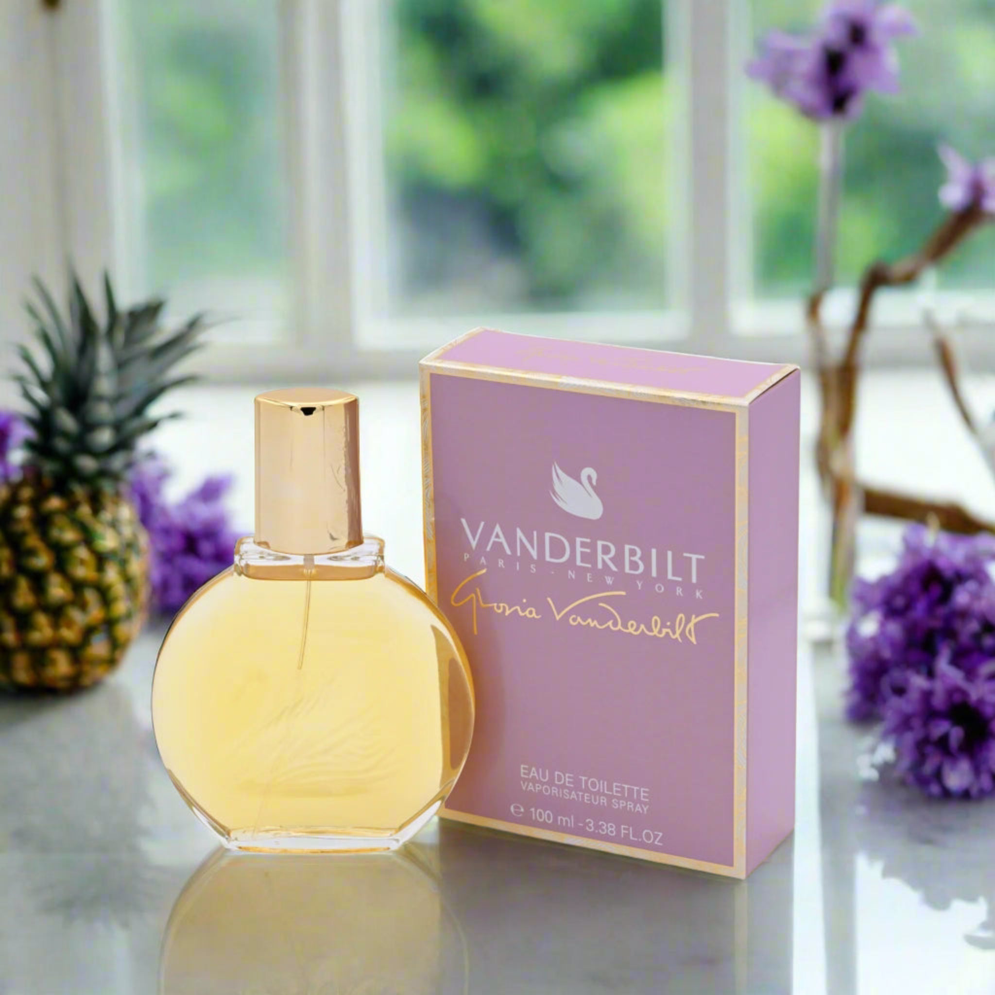 Vanderbilt perfume bottle and packaging on a reflective surface with blurred greenery in the background