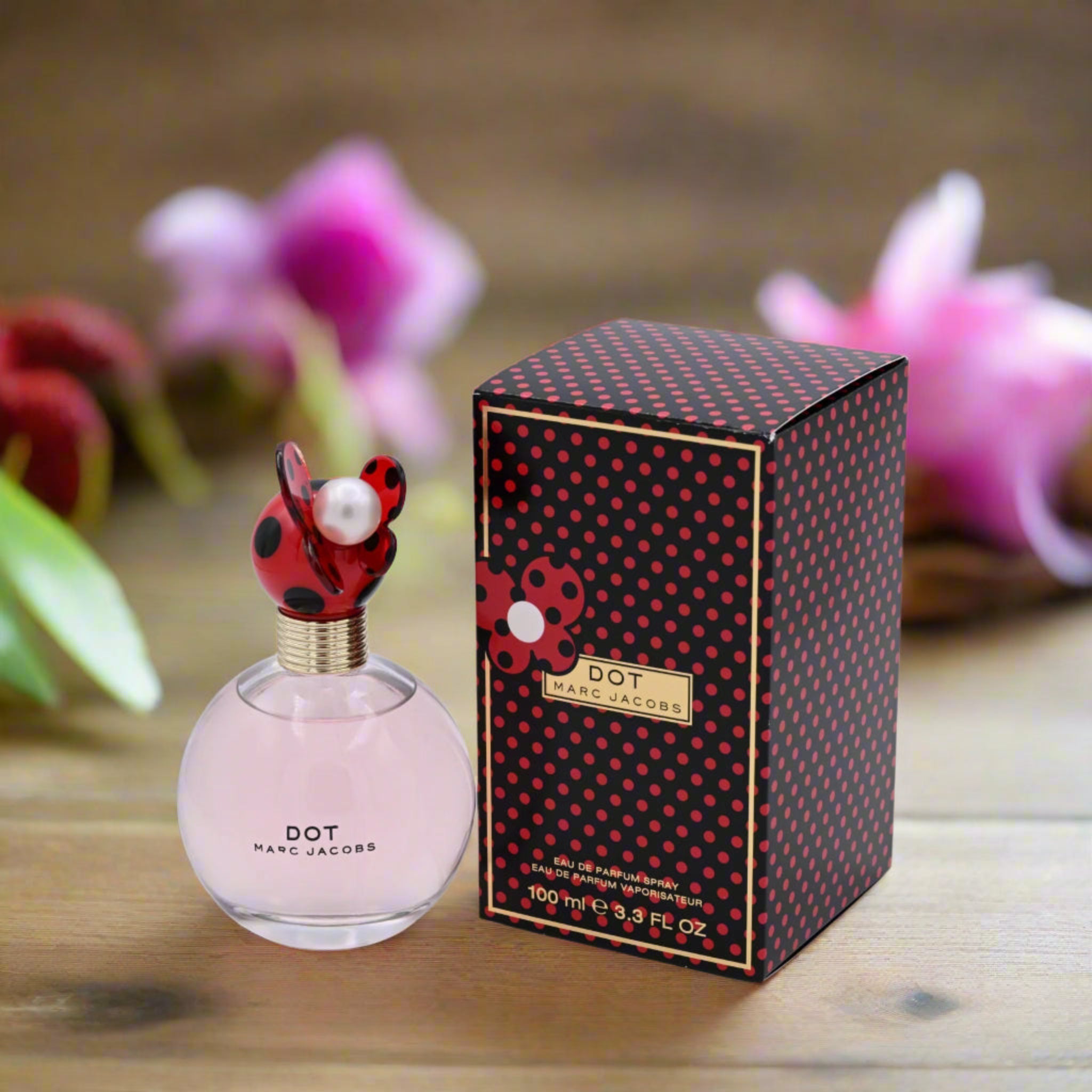 Marc Jacobs Dot perfume bottle and packaging on a wooden surface with flowers in the background