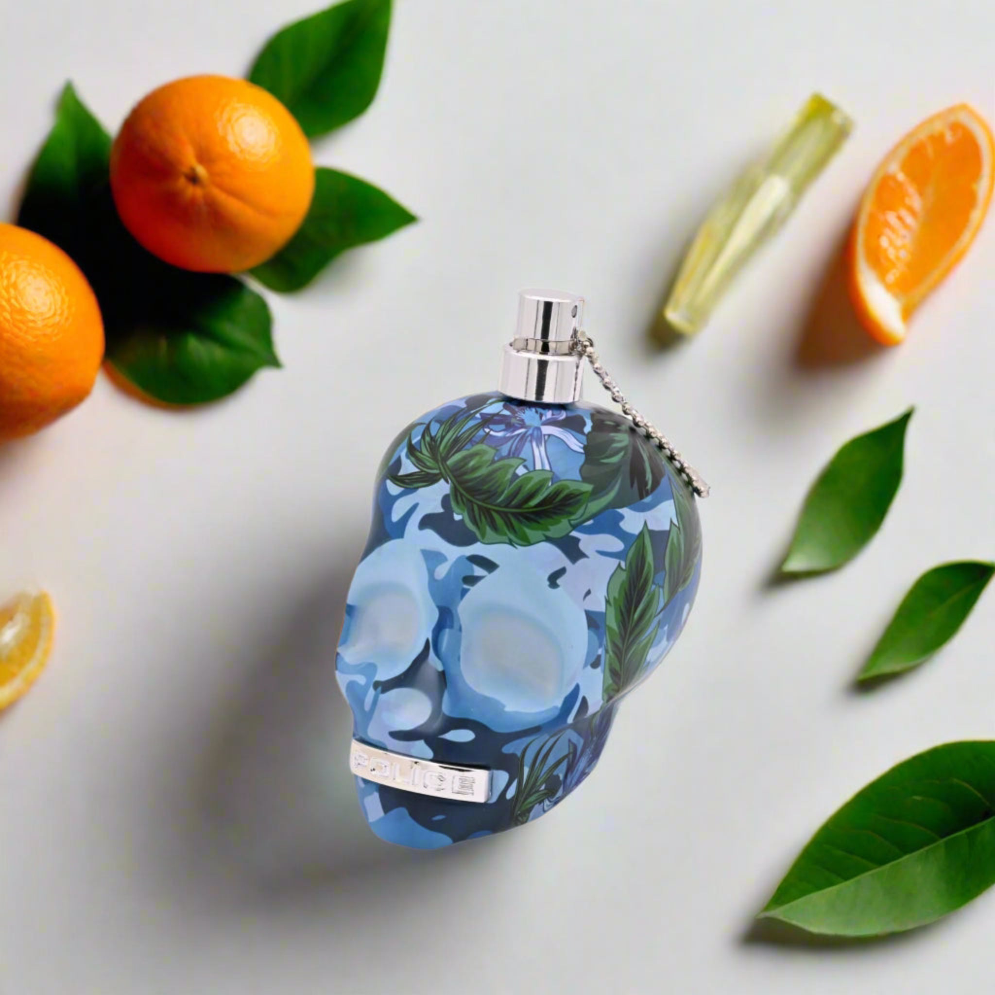 Perfume bottle with floral design surrounded by oranges and leaves on a light background