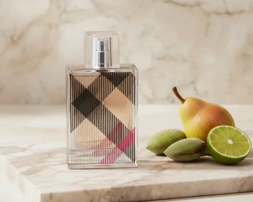 Burberry Brit for Her perfume in a clear check-pattern bottle with pink stripes, beside a pear, almonds and lime.