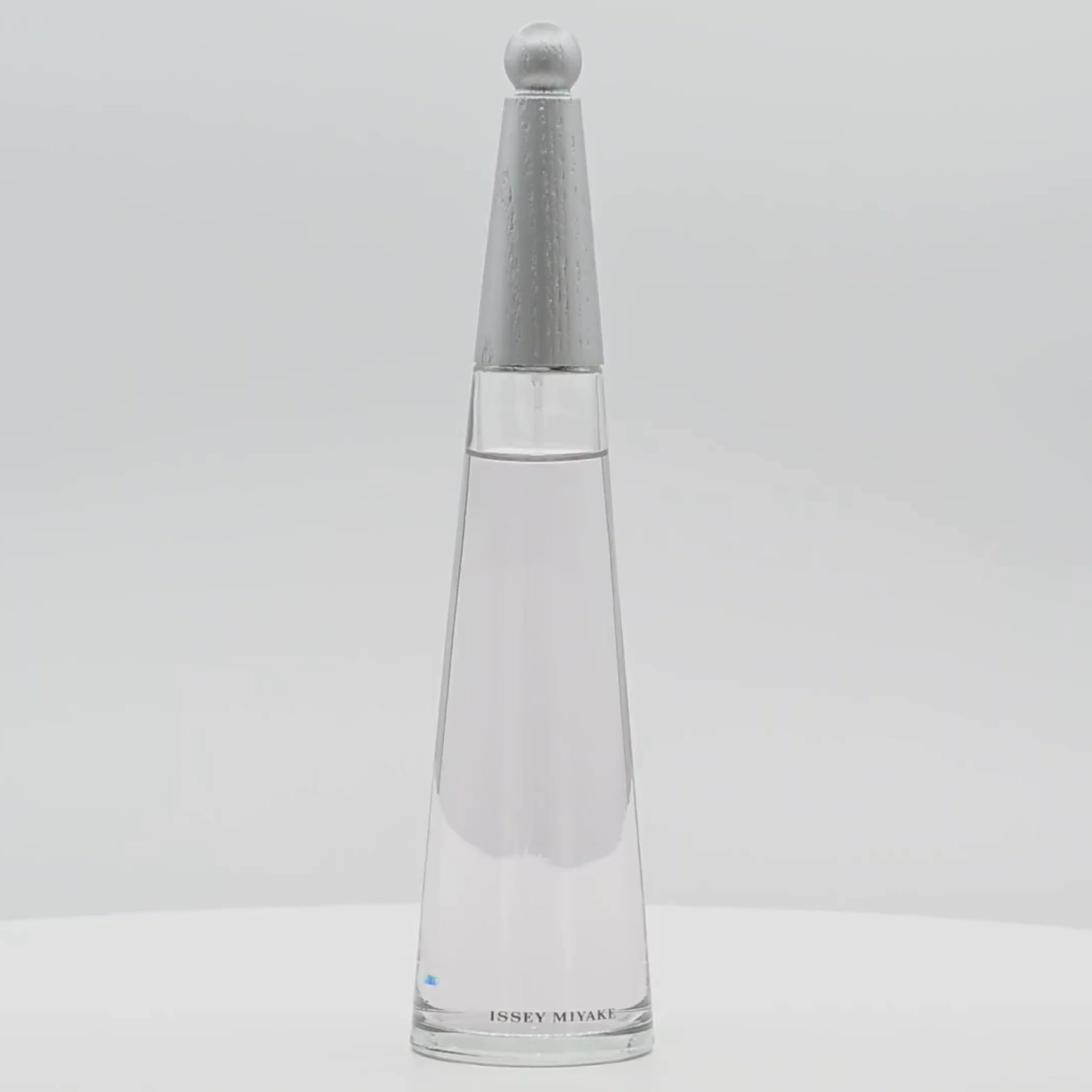 Issey Miyake L'Eau d'Issey perfume bottle rotating on a white podium