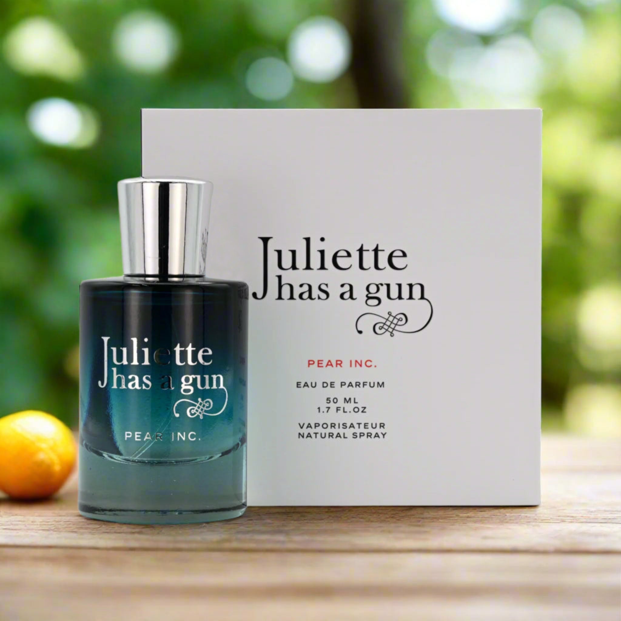 Perfume bottle and packaging of 'Juliette has a gun' on a wooden surface with a blurred green background