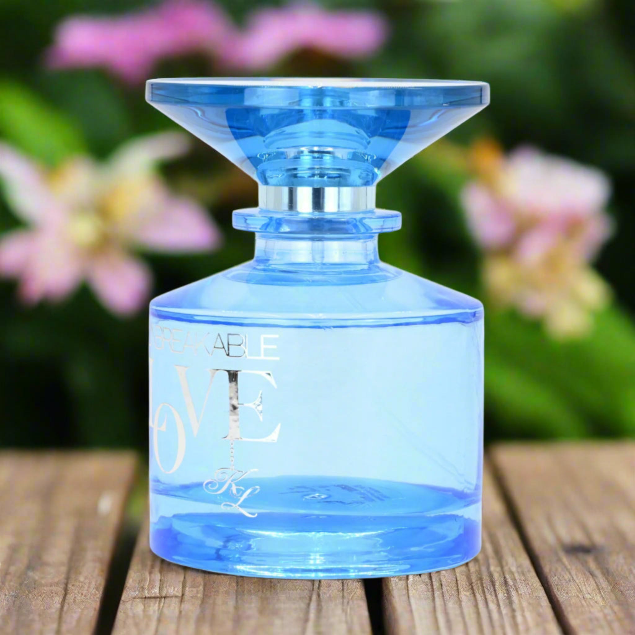 Blue perfume bottle on a wooden surface with flowers in the background