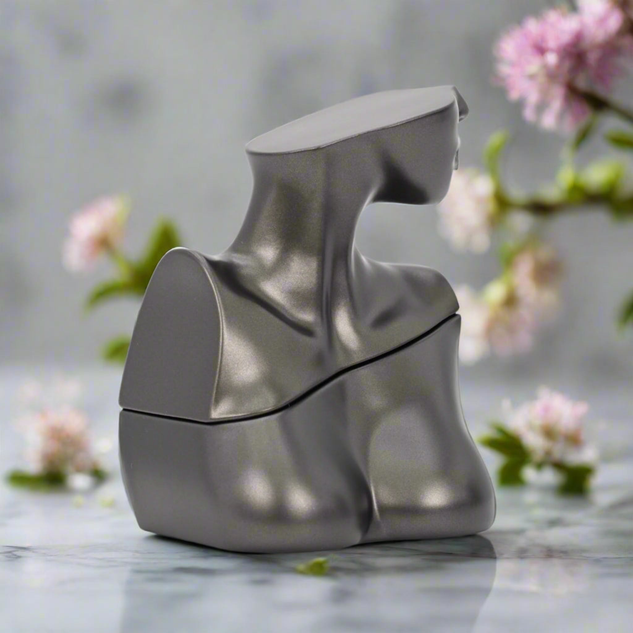Silver and white kitchen knife sharpener on a marble surface with blurred flowers in the background